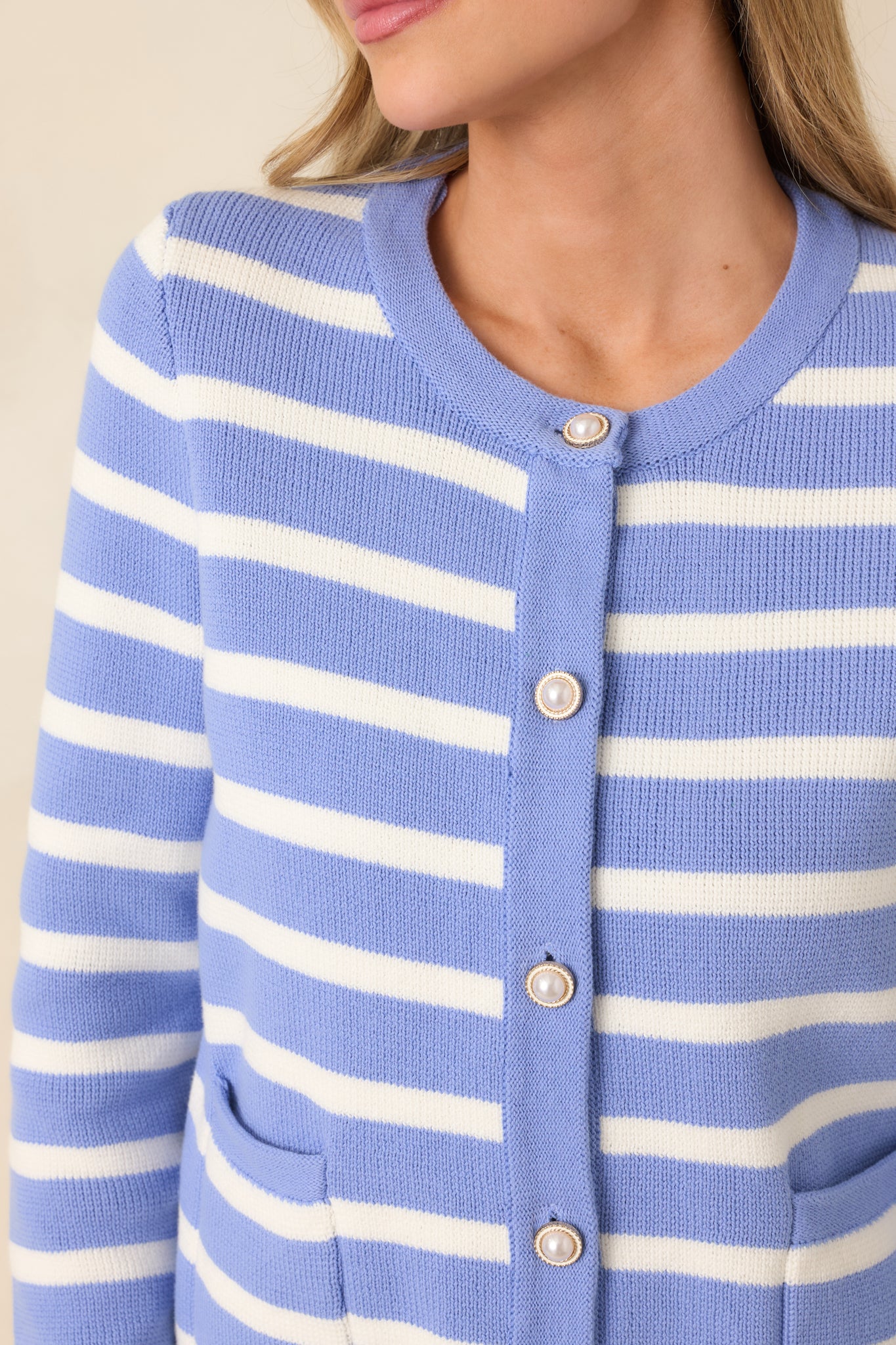 Close-up detail of the gold-tone buttons on the blue striped cardigan’s button-front closure.