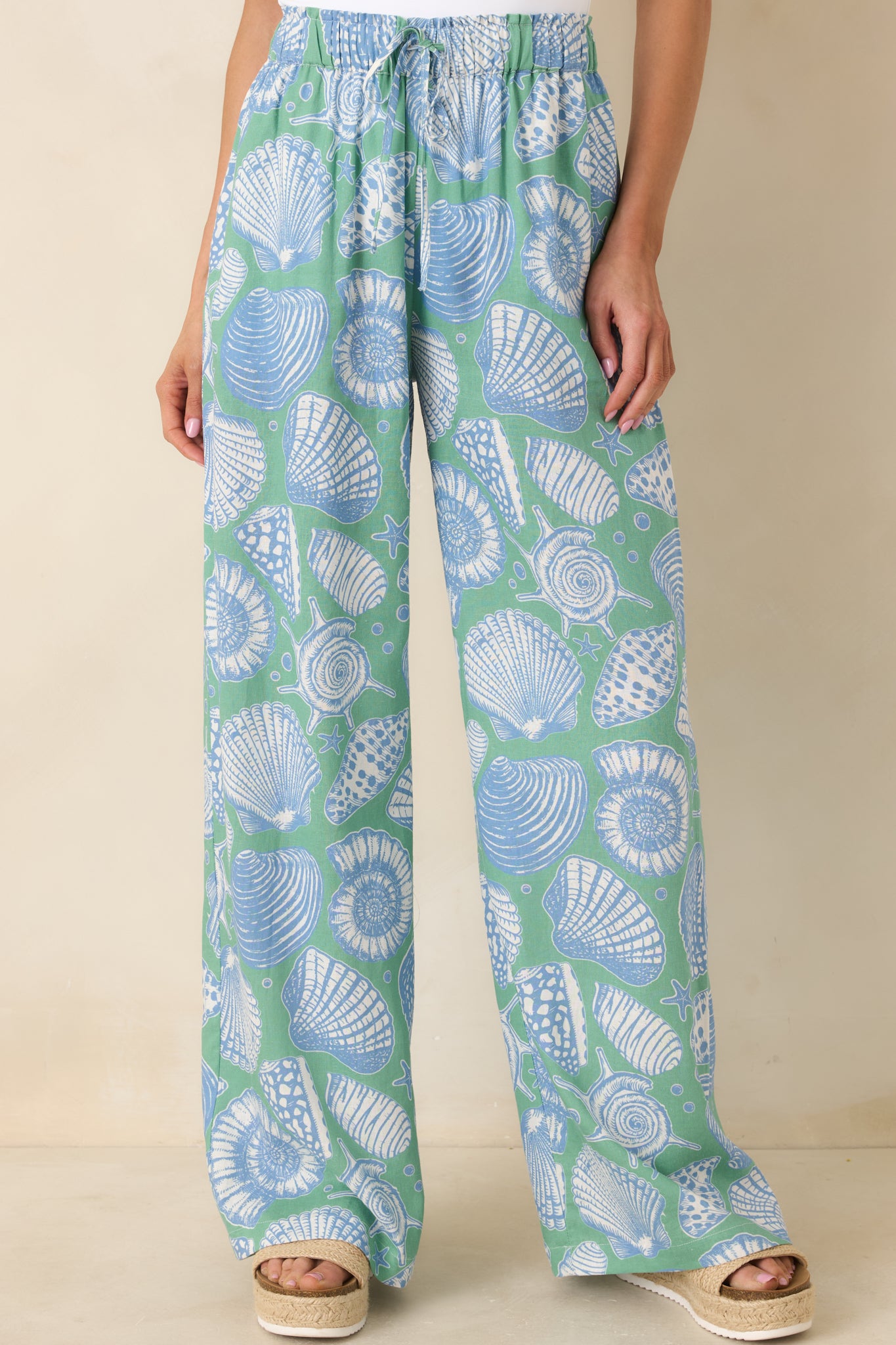 Close-cropped image of the elastic waistband with adjustable drawstring detail on the shell print pants.