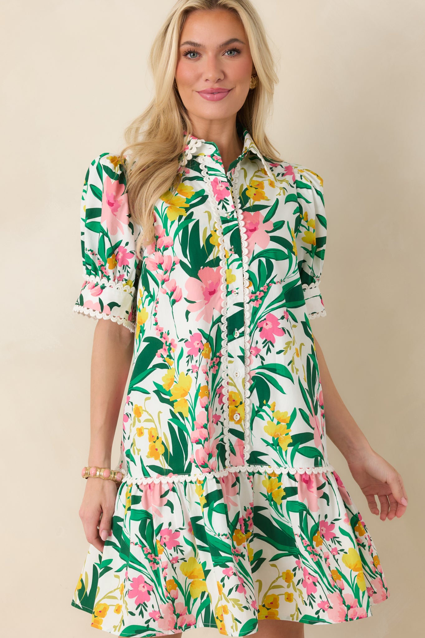 Cropped look focusing on the drop waist, flouncy ruffle hem, and vibrant green, pink, and yellow floral print.