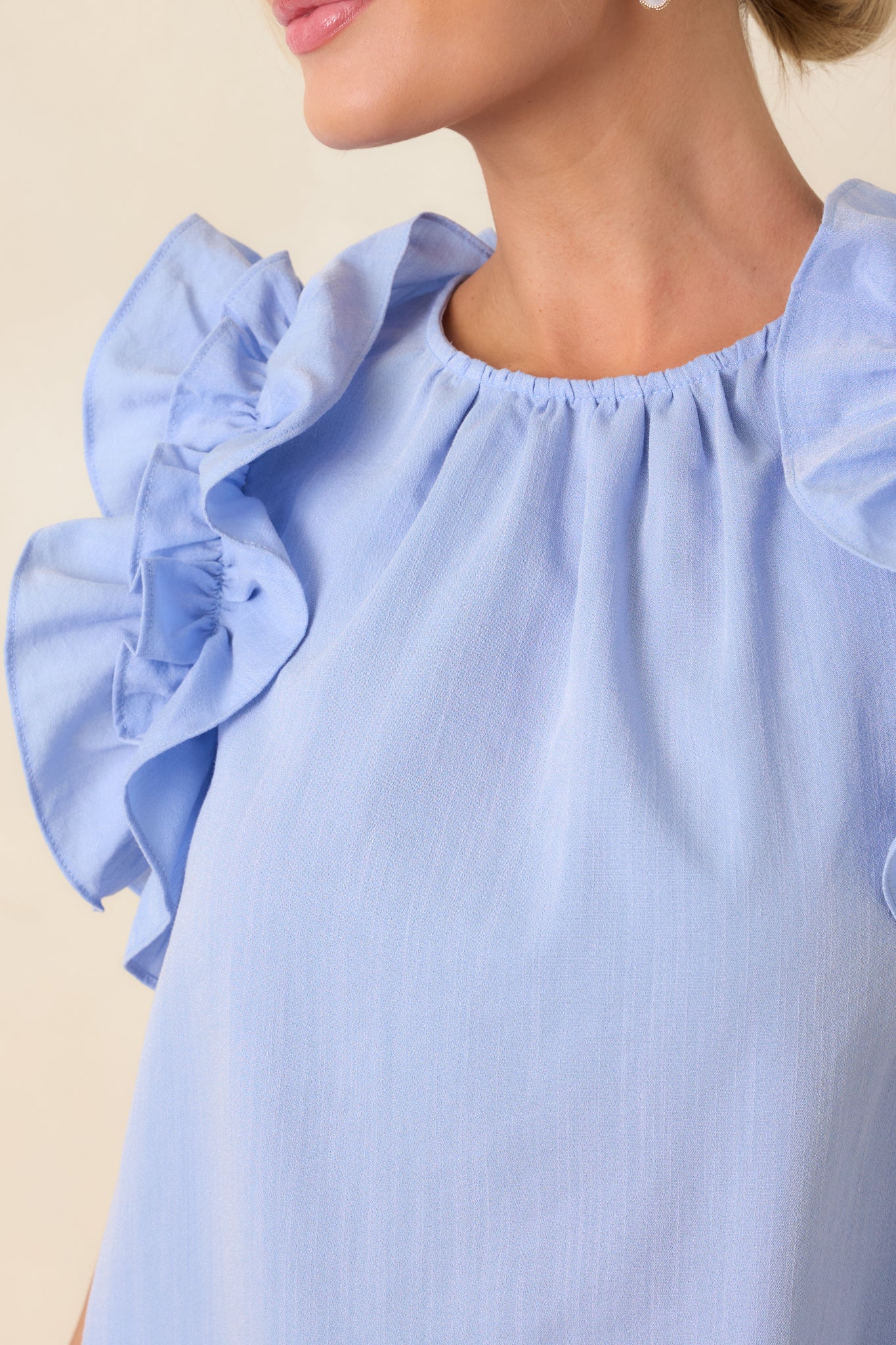 Close-up of light blue neckline and ruffled shoulder seam detail.