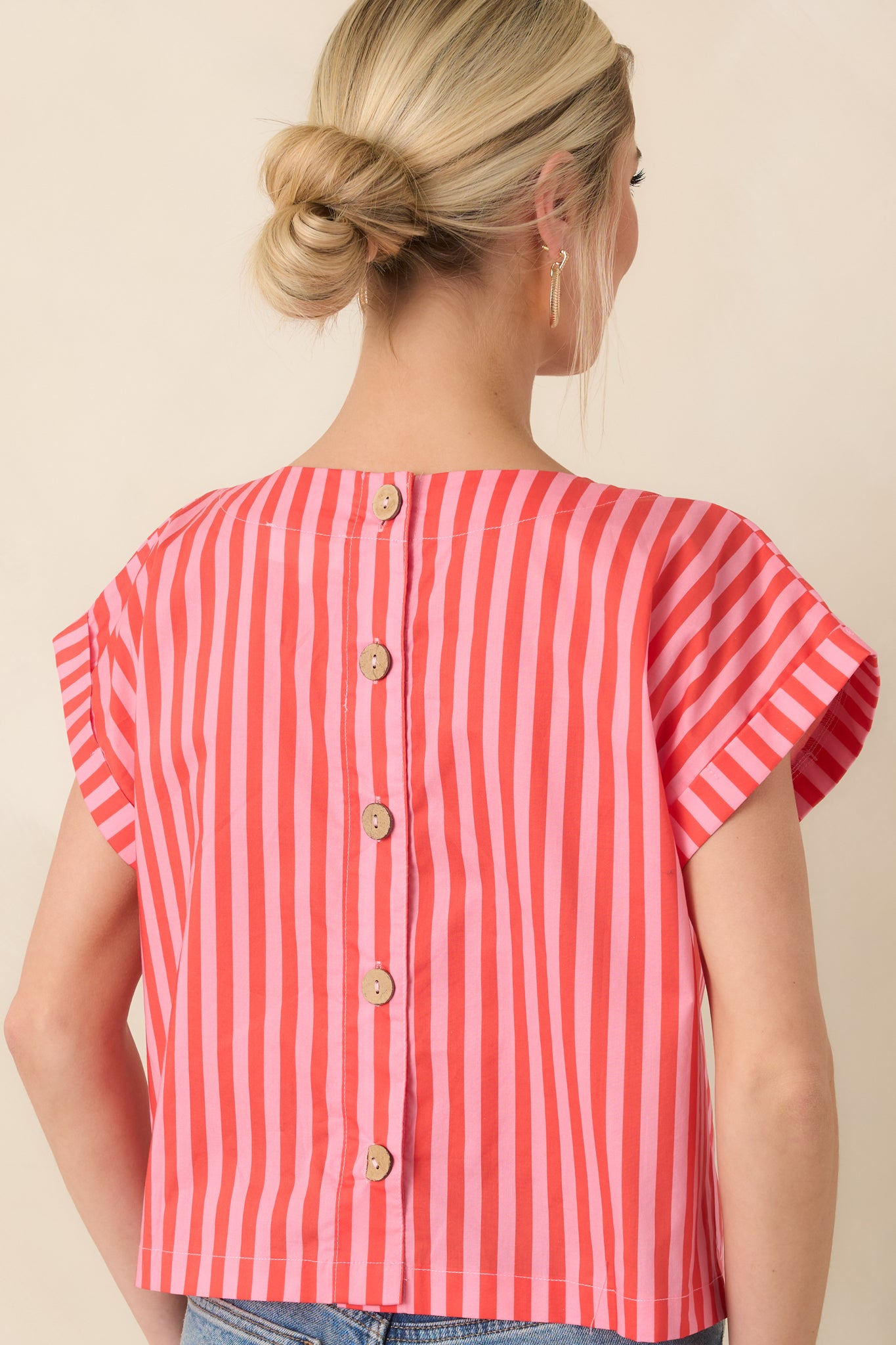 Rear of the striped cotton top featuring vertical orange and pink detailing and functional button closures for added visual interest.