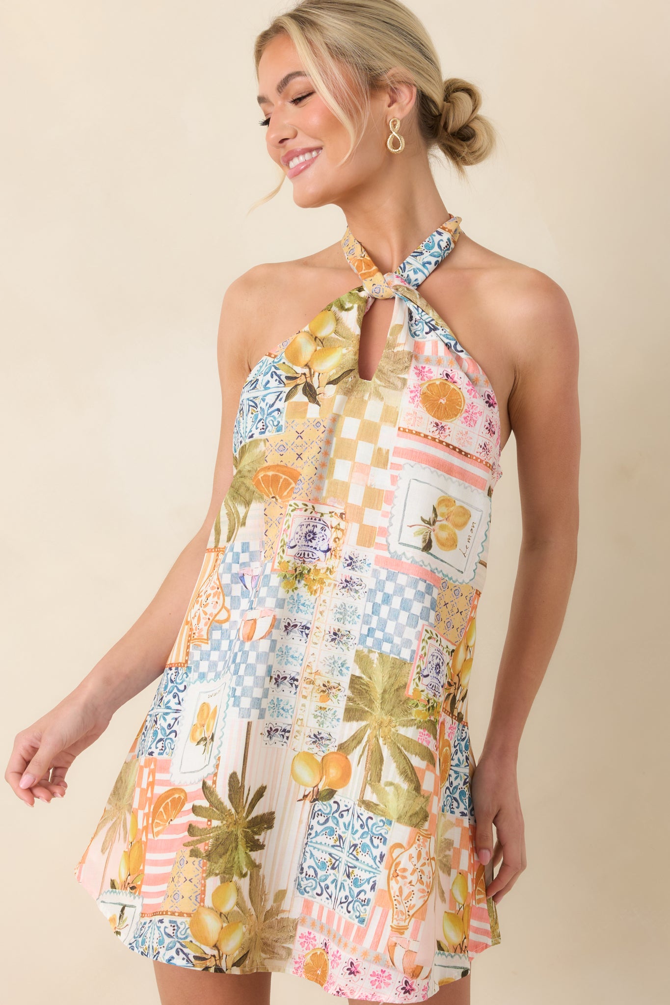 Close-up highlighting the twisted halter neckline and subtle front keyhole of the tropical print mini dress.