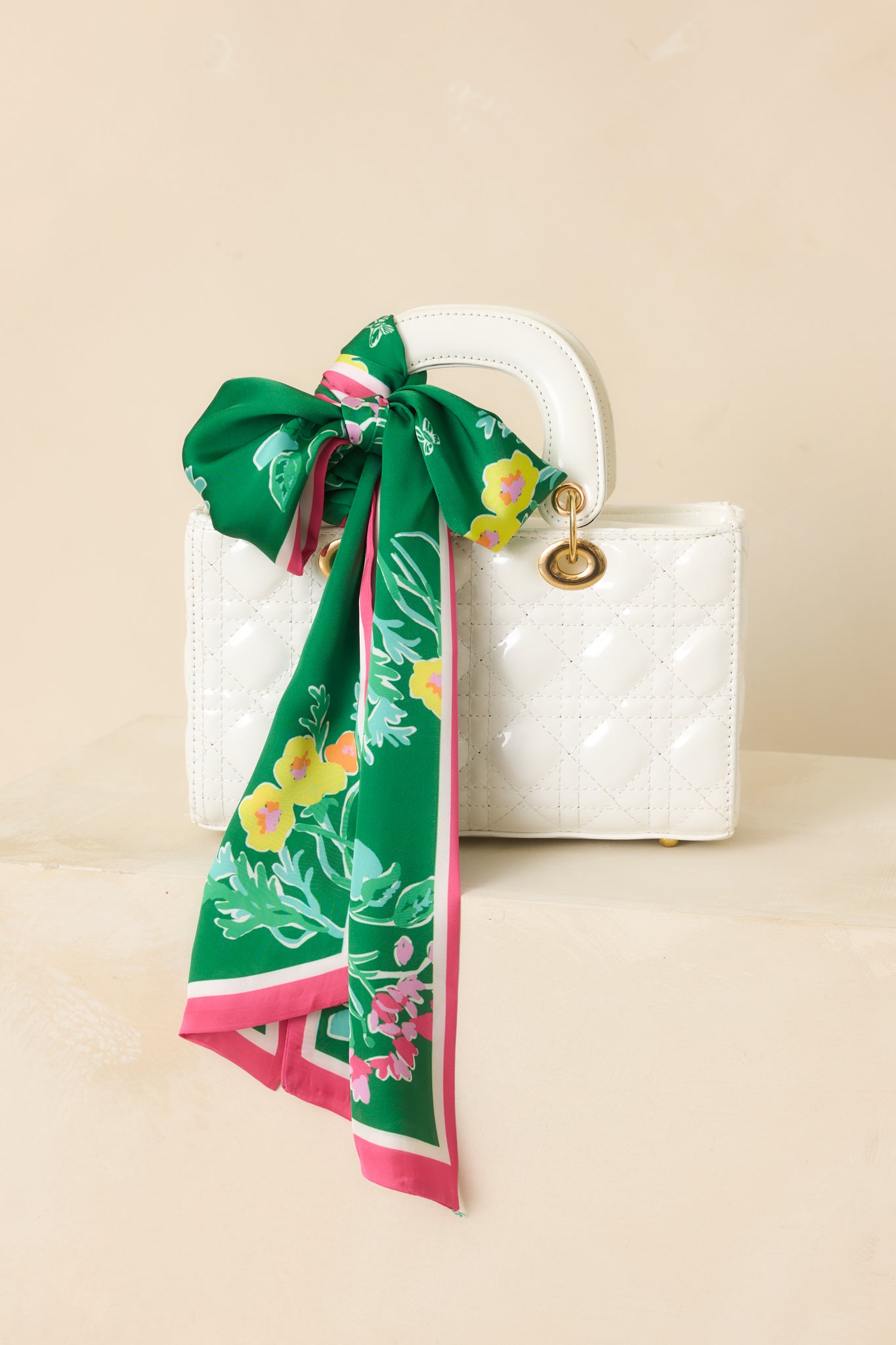 Cropped view highlighting the green fabric, small floral details, and pink border of the slim scarf.