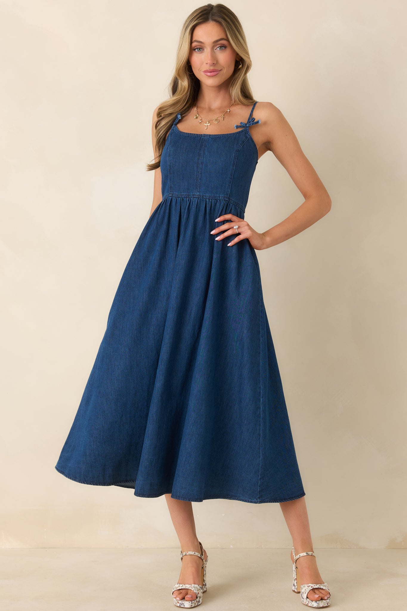 Timeless dark wash midi with adjustable straps, bow details at the shoulders, and a relaxed gathered skirt that moves with ease.