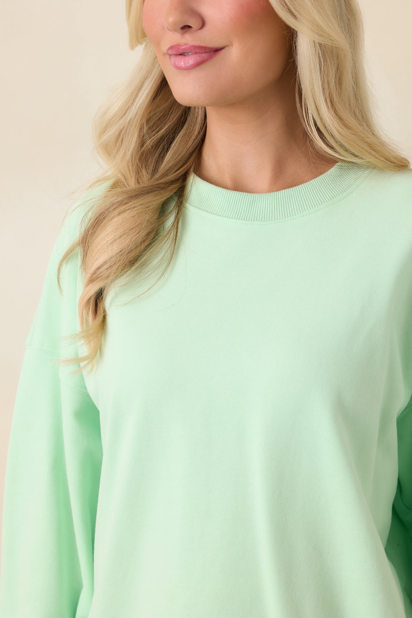 Close-up of mint green crewneck showing ribbed trim, smooth knit fabric, and soft texture.