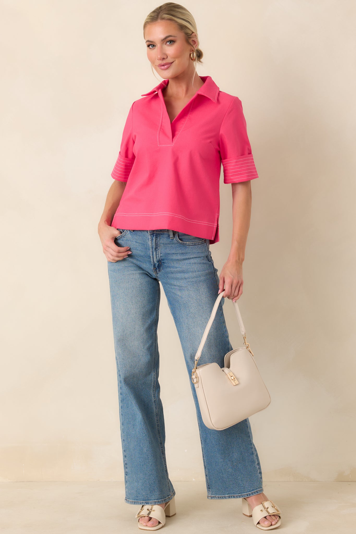 Hot pink top with structured collar, open V-neckline, and short wide sleeves with stitched cuff accents.