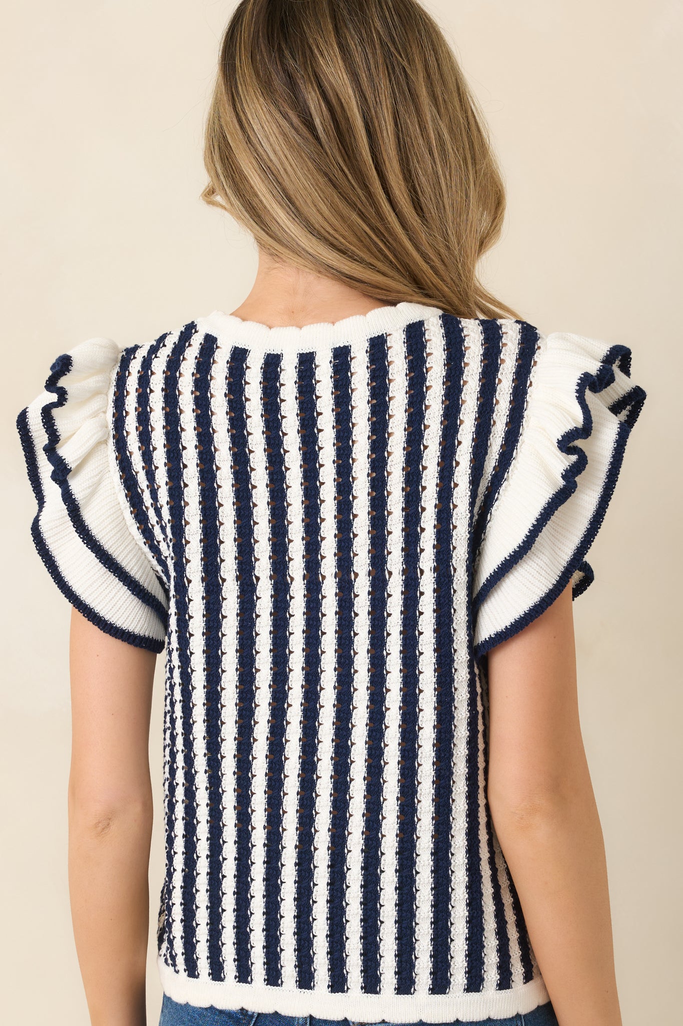 Rear view of striped top showing flutter sleeves and scalloped hemline.