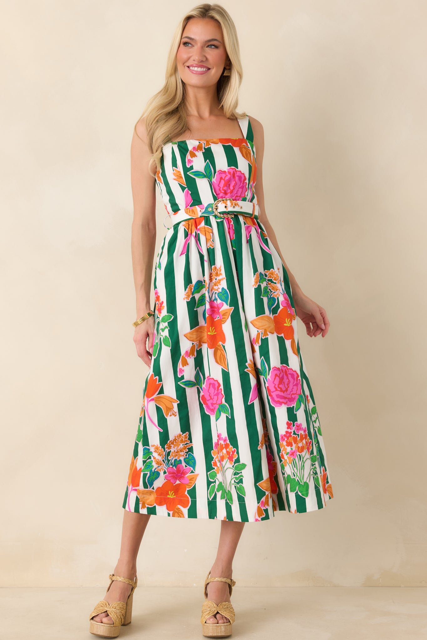 Green striped midi dress covered in colorful blooms, designed with a fitted bodice, coordinating belt with gold buckle, and a full skirt that creates graceful movement.