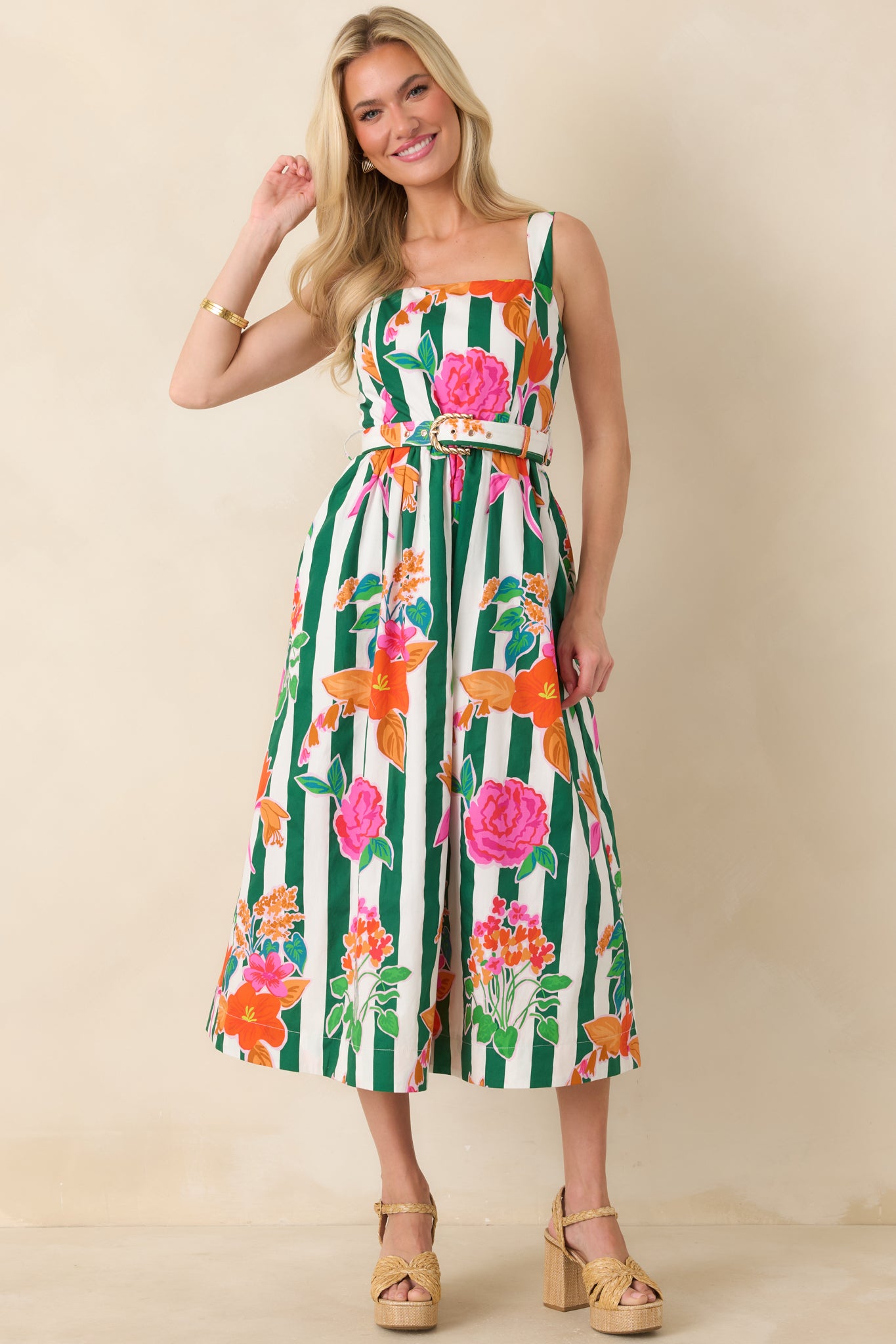 Cotton midi dress with vibrant floral print over crisp green vertical stripes and a coordinating belt with a gold buckle shaping the waist above a flowing full skirt.
