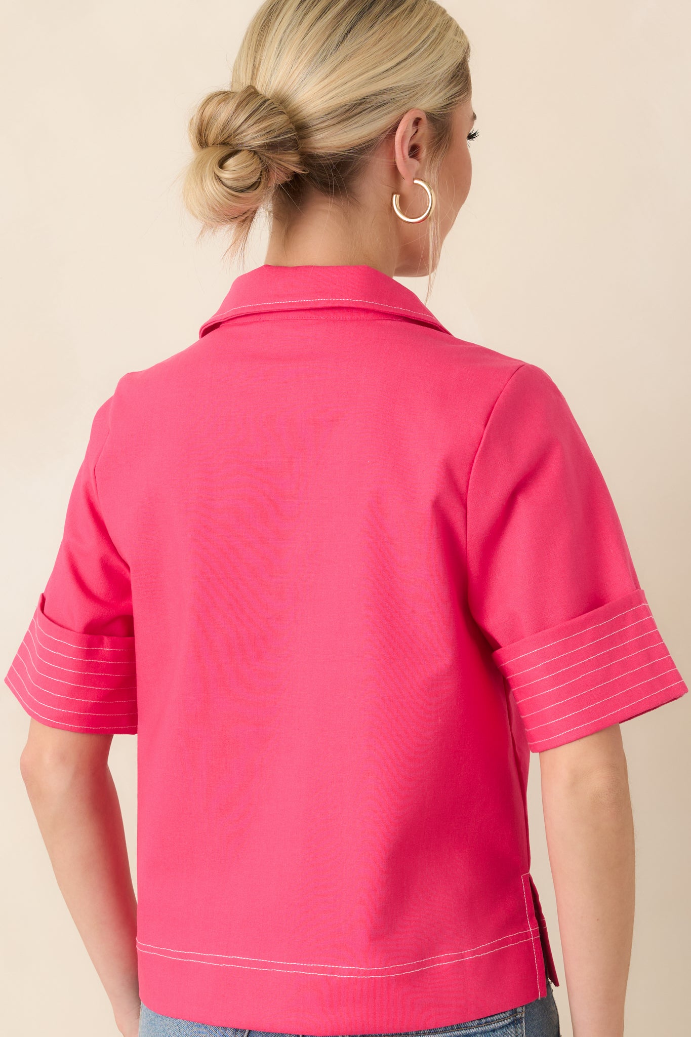 Rear view of the hot pink top displaying the straight hem, short wide sleeves, and contrast stitching.