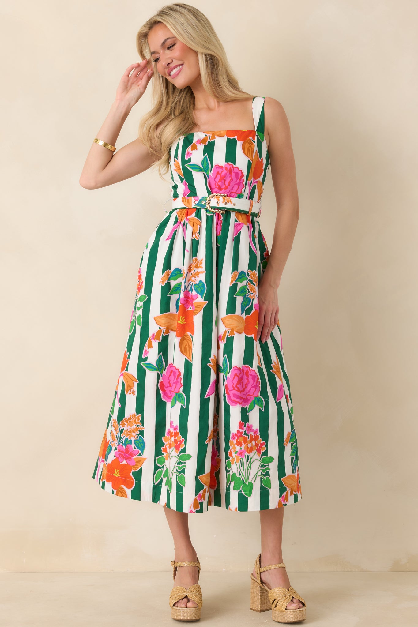 Cotton midi showcasing bright floral clusters over vertical green stripes, finished with a structured bodice, waist-defining belt, and a flowing skirt silhouette.