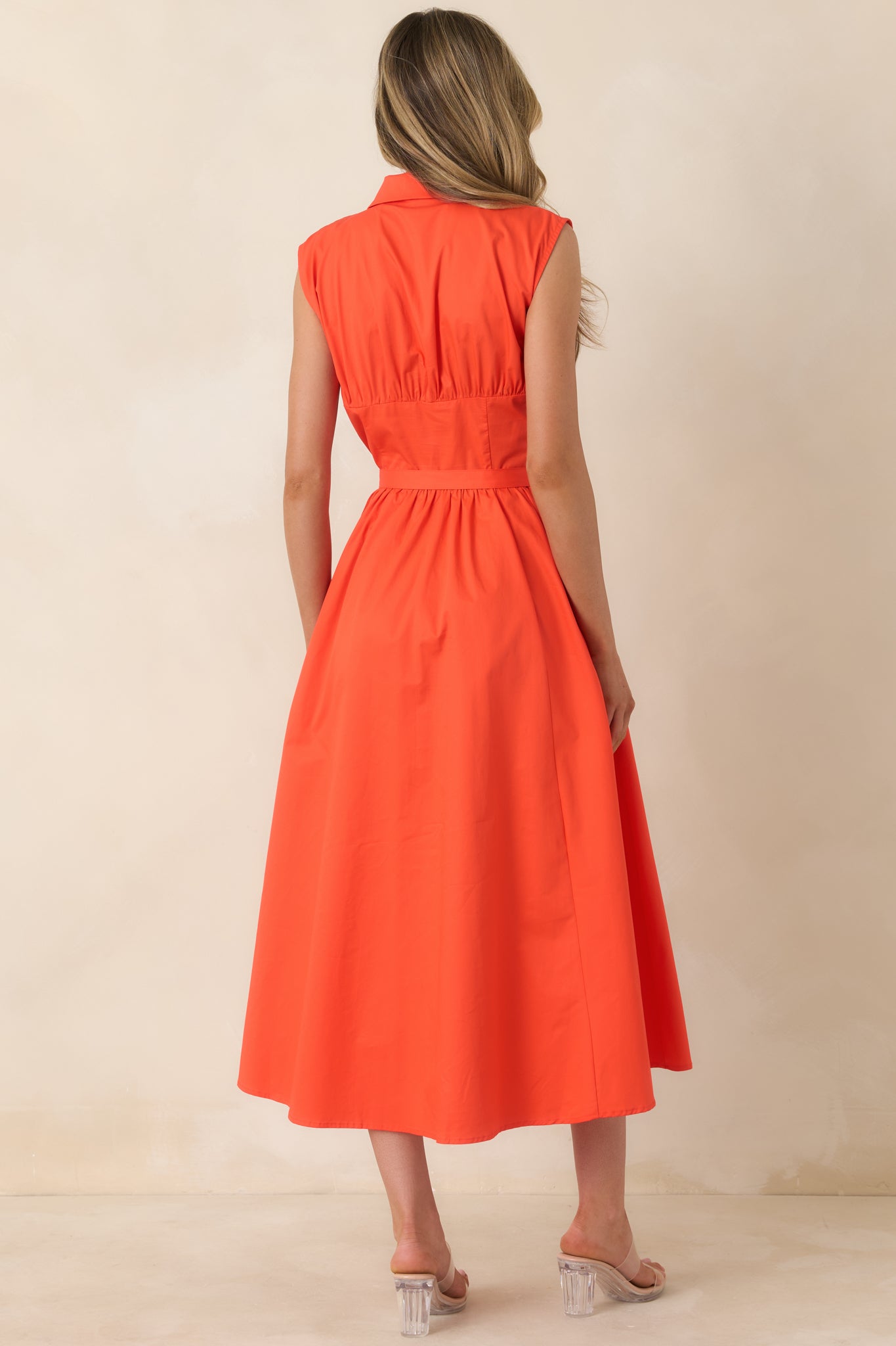 Sleeveless cotton midi dress with defined waist and softly flowing skirt.