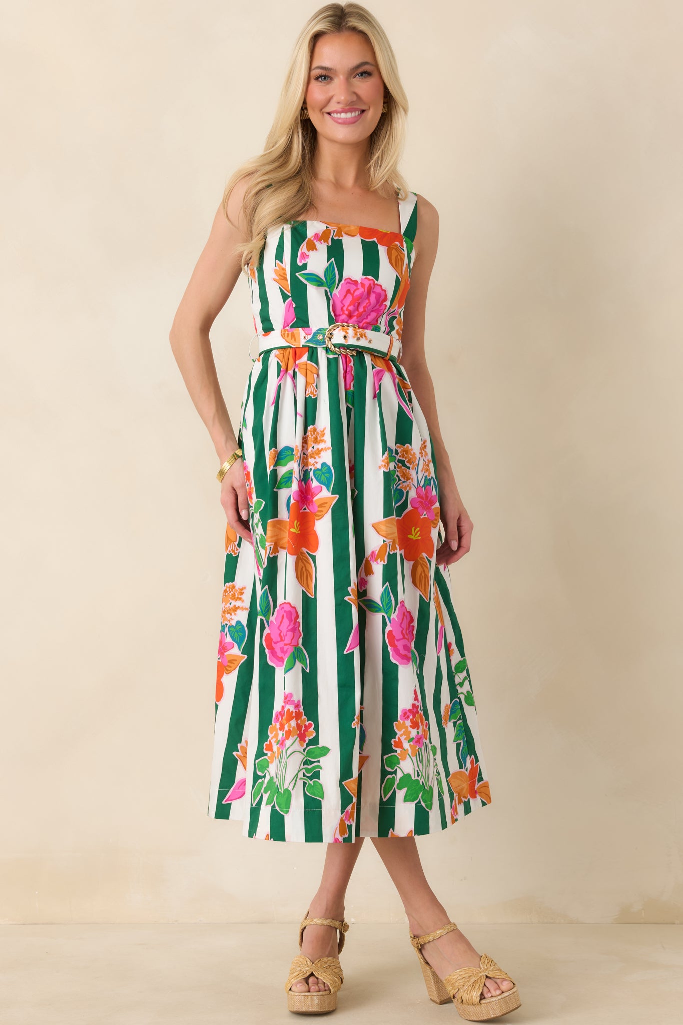 Playful floral midi dress with crisp green stripes, a tailored bodice, coordinating belt with gold buckle, and a voluminous skirt that drapes elegantly.