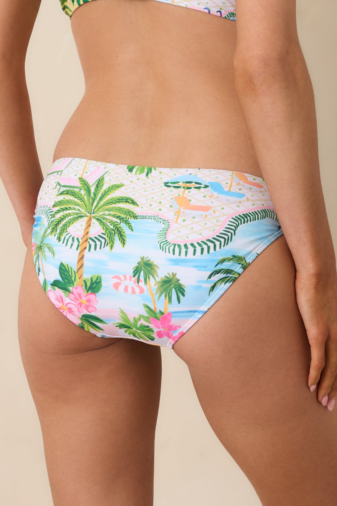 Back view of low-rise bikini bottoms displaying the colorful tropical poolside print across the full rear.