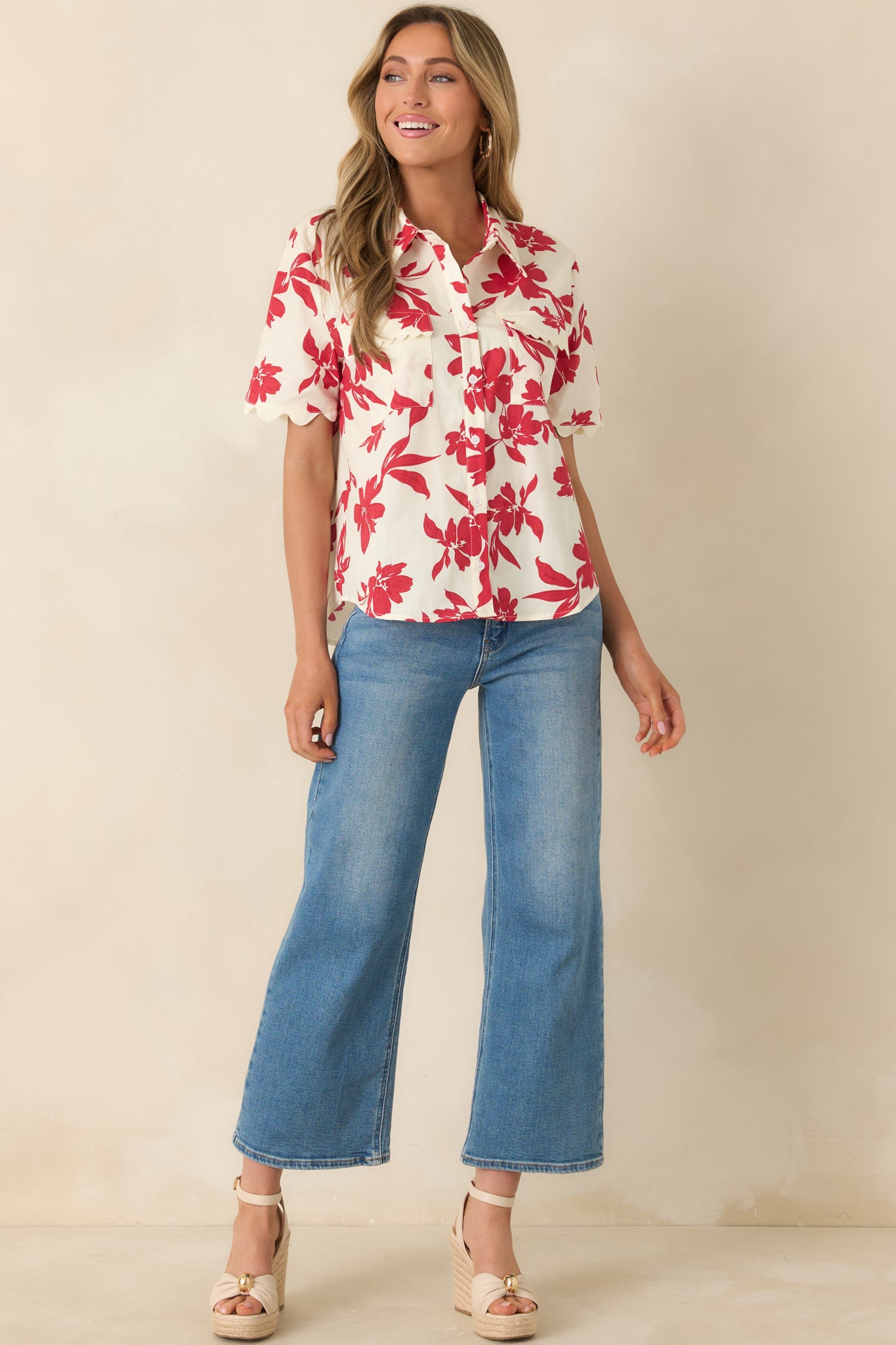Ivory cotton top with bold red floral print, collared neckline, and button-front closure.