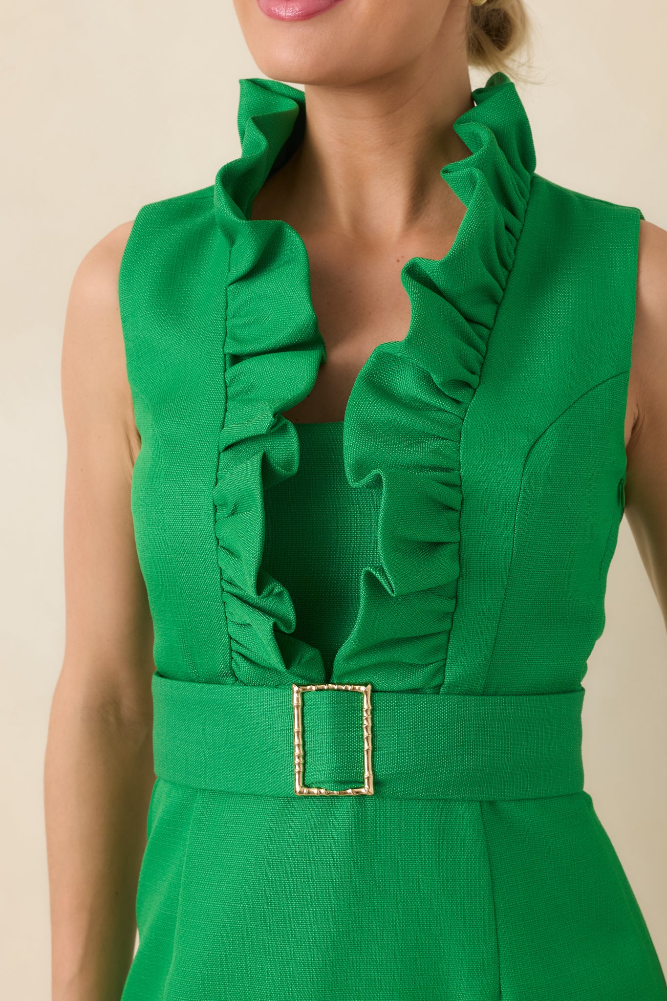 Close-up of the vibrant green fabric showcasing the ruffle-trimmed neckline and coordinating belt with gold buckle.