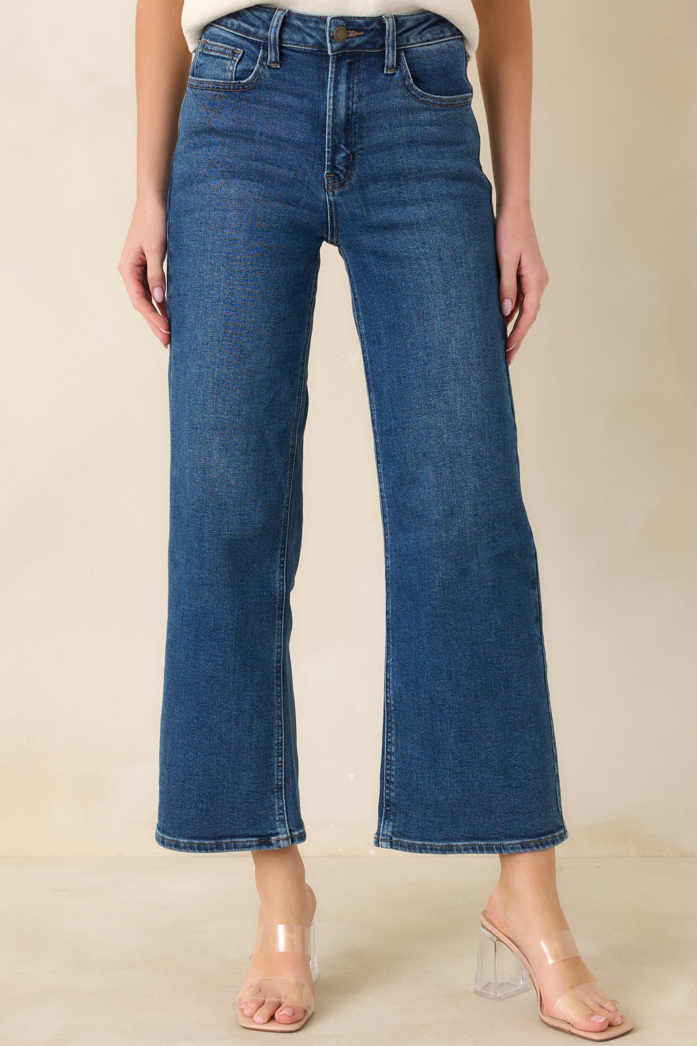 Detailed cropped front view of dark wash jeans showing high-rise fit and cropped hem finish.