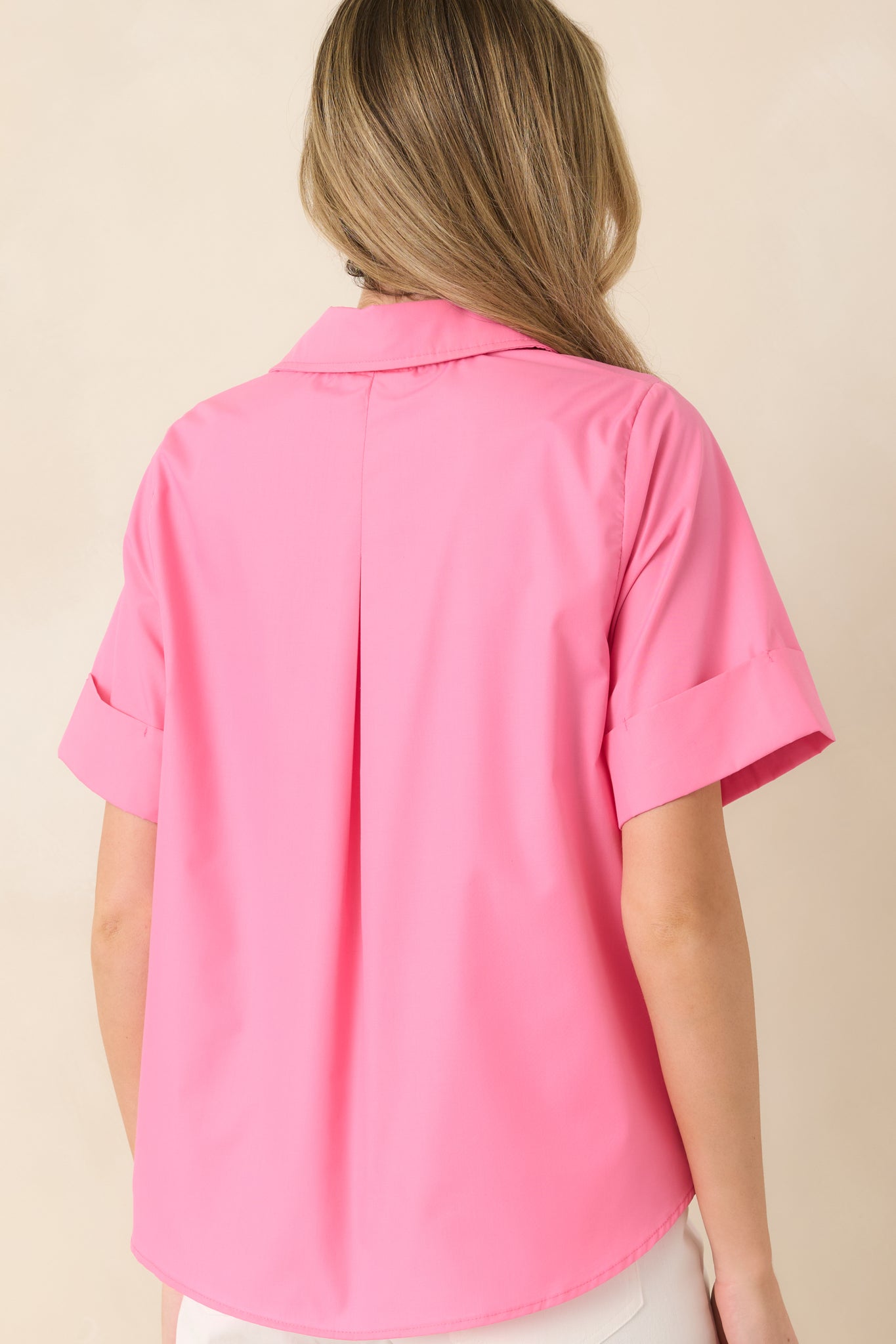 Rear view of the pink blouse displaying the subtle pleat detail and softly rounded hem for added movement.