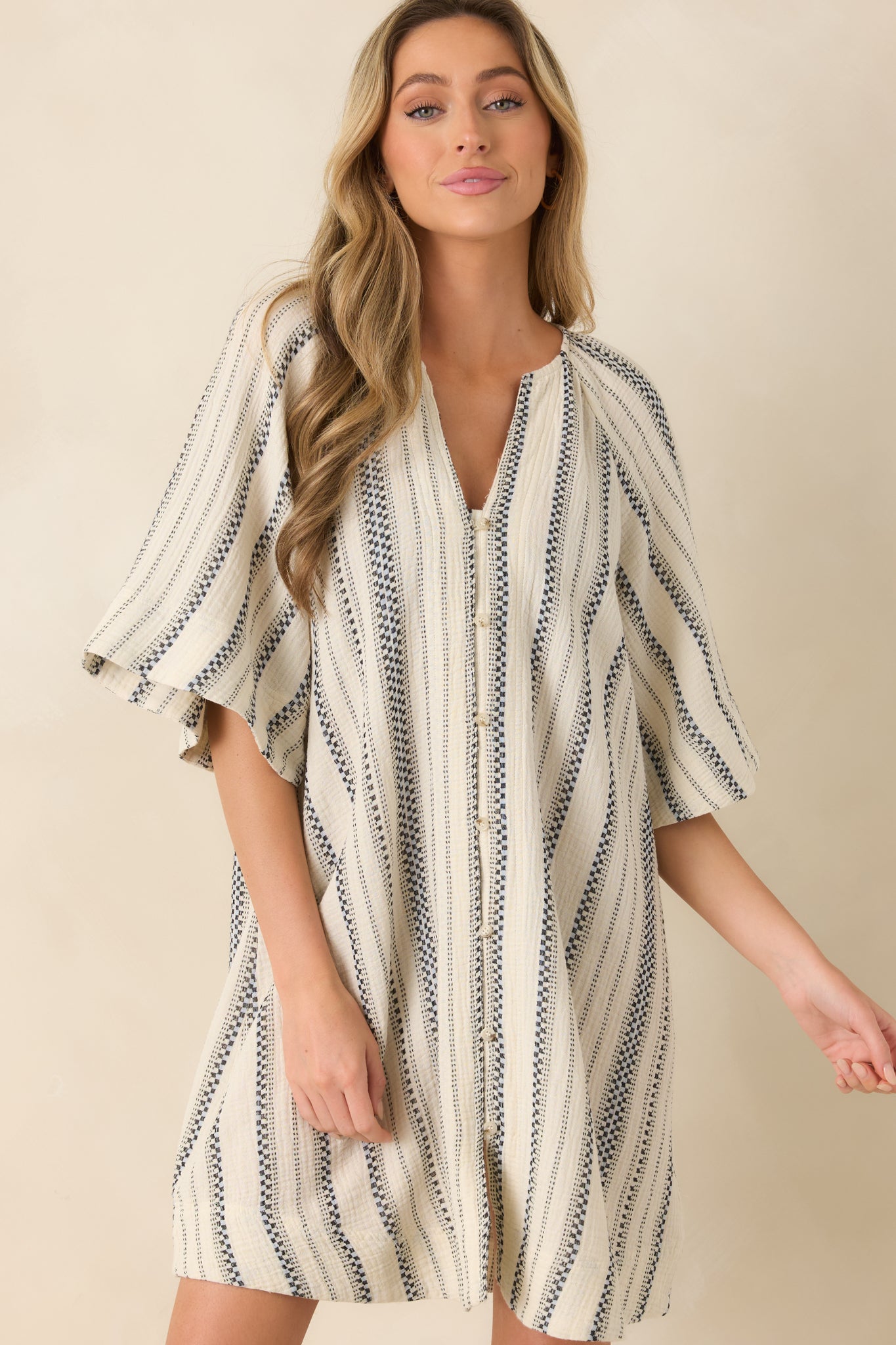 Button front neckline detail on striped mini dress with breathable cotton texture.