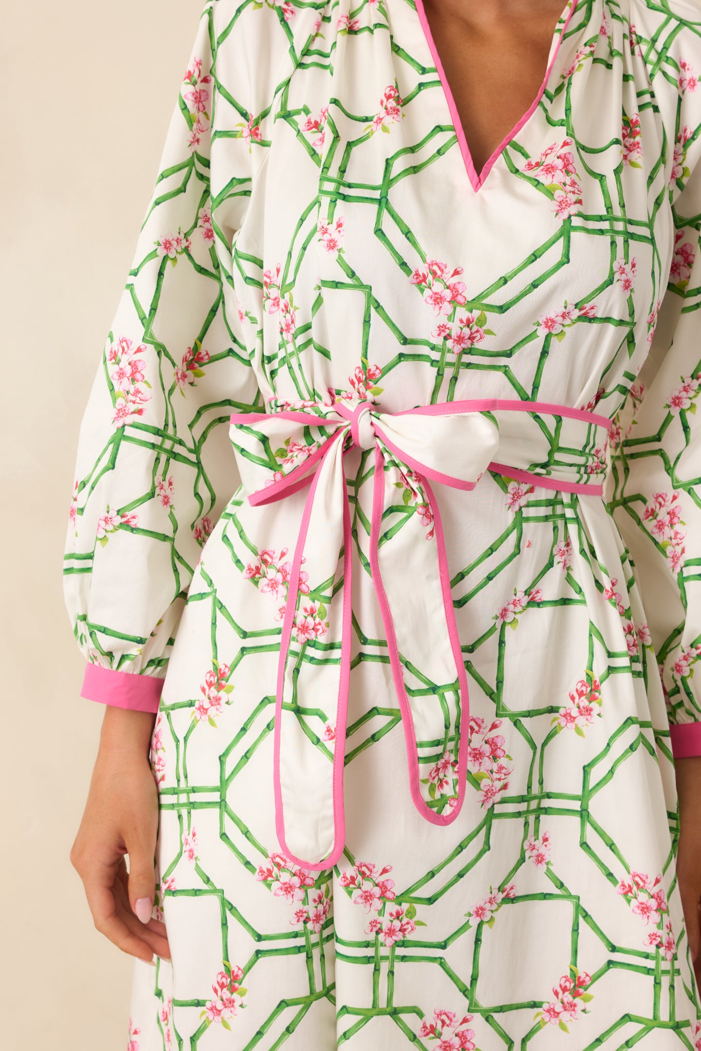 Close view of the floral trellis print fabric highlighting contrast trim at the split neckline and pink cuff detailing.