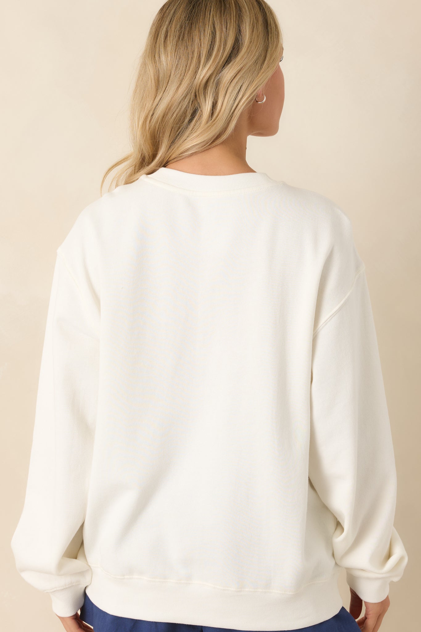 Back view of the ivory sweatshirt displaying a clean, minimal finish with relaxed shaping and ribbed trim at the cuffs and hem.