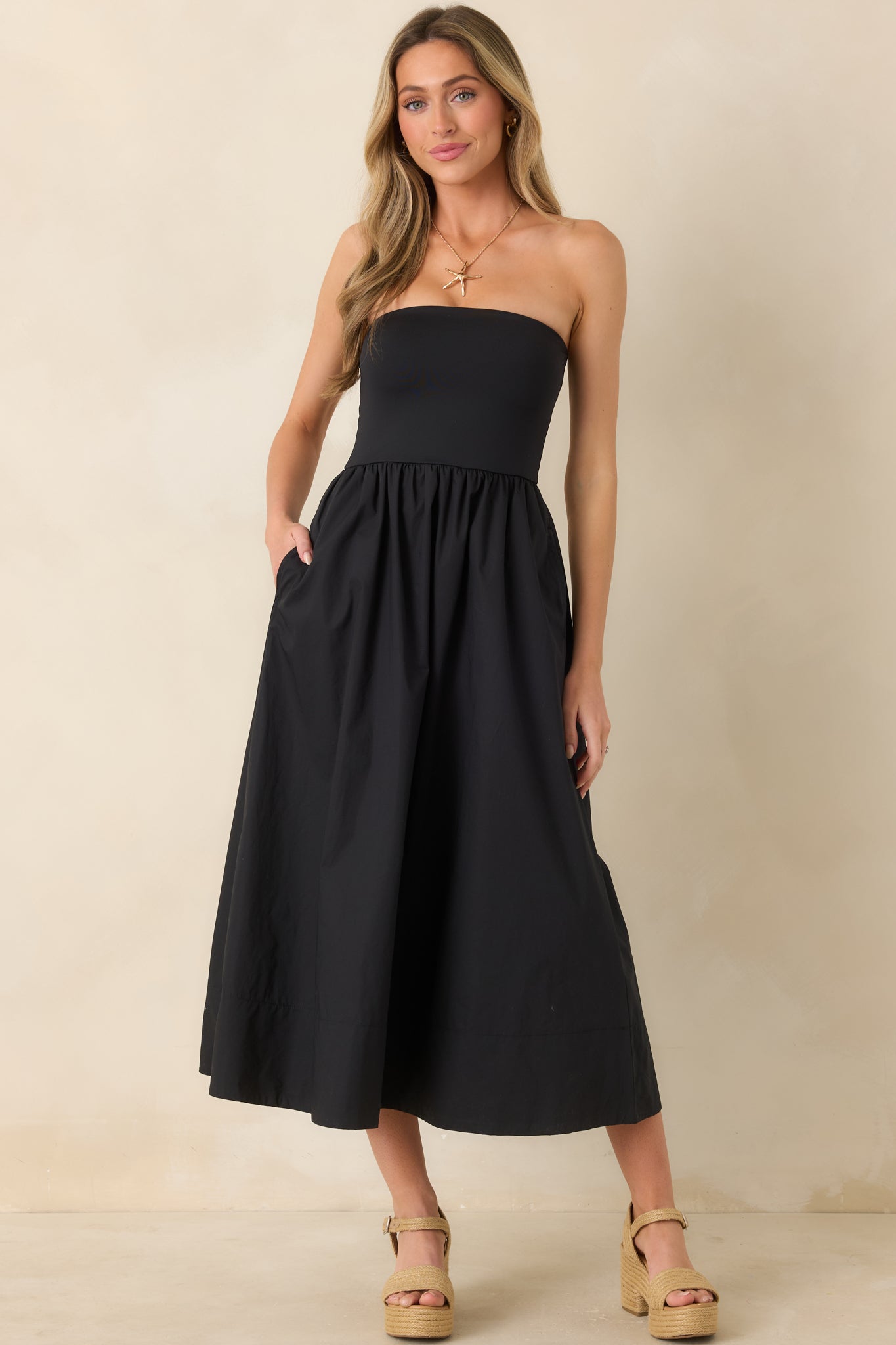 Front view of strapless black midi dress showcasing smooth bodice and flowing silhouette.