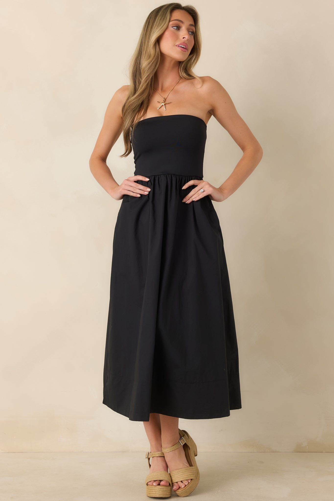 Front-facing angle of black strapless dress emphasizing the clean neckline and feminine drape.