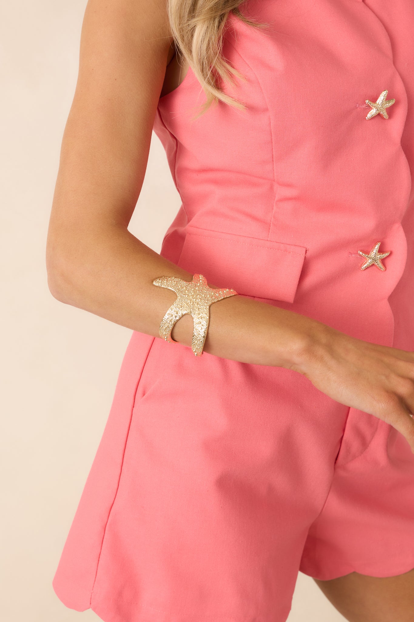 Close cropped angle of gold bracelet highlighting starfish shape and mixed-size beaded detailing.