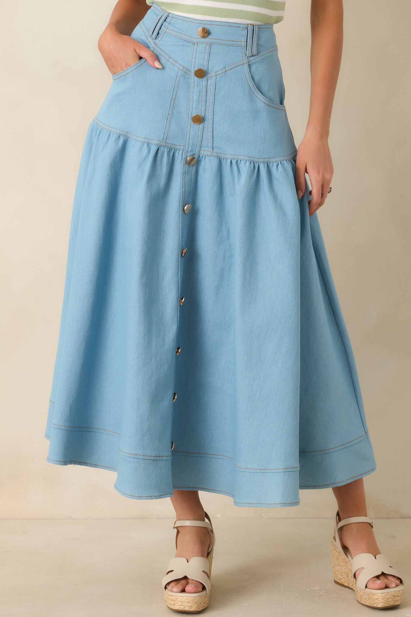 Close view of light wash denim fabric showing structured waistband, front pocket detail, and button accents.