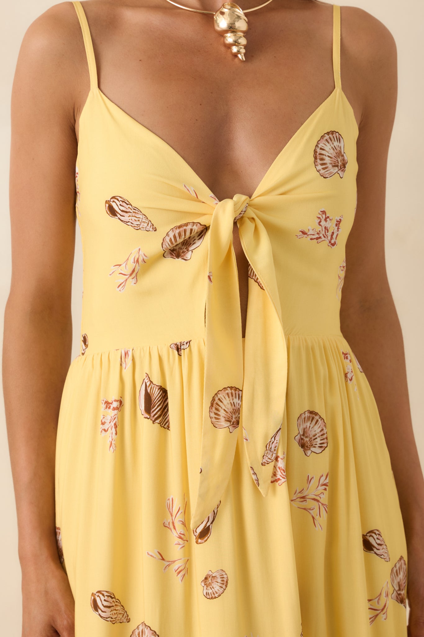 Close-up of yellow seashell print fabric highlighting the front-tie bodice, delicate cutout, and soft texture.
