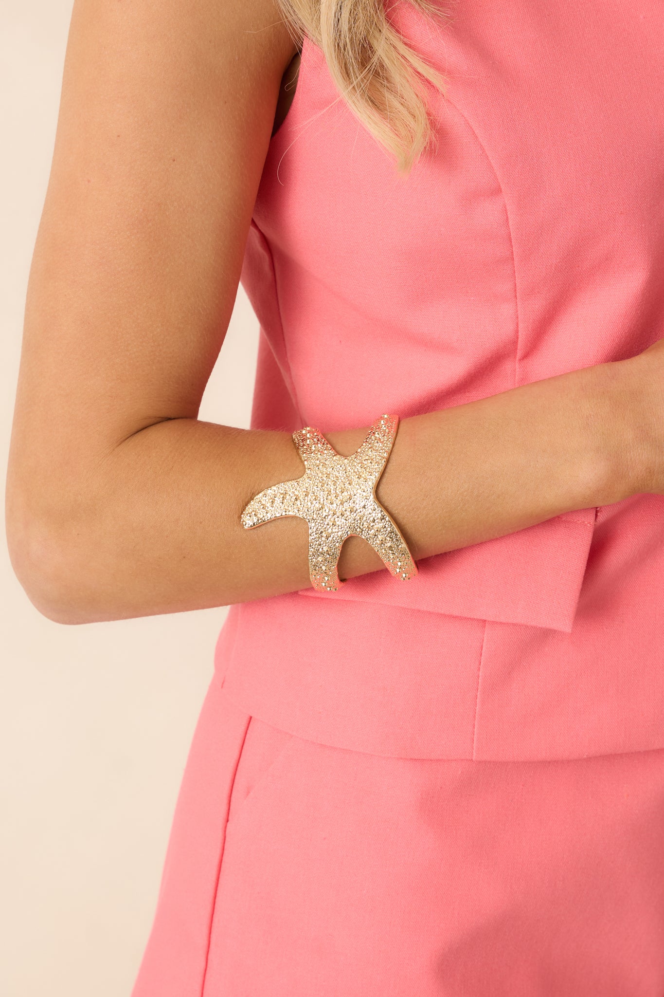 Cropped view of gold starfish bracelet featuring textured gold beads and an open adjustable design.