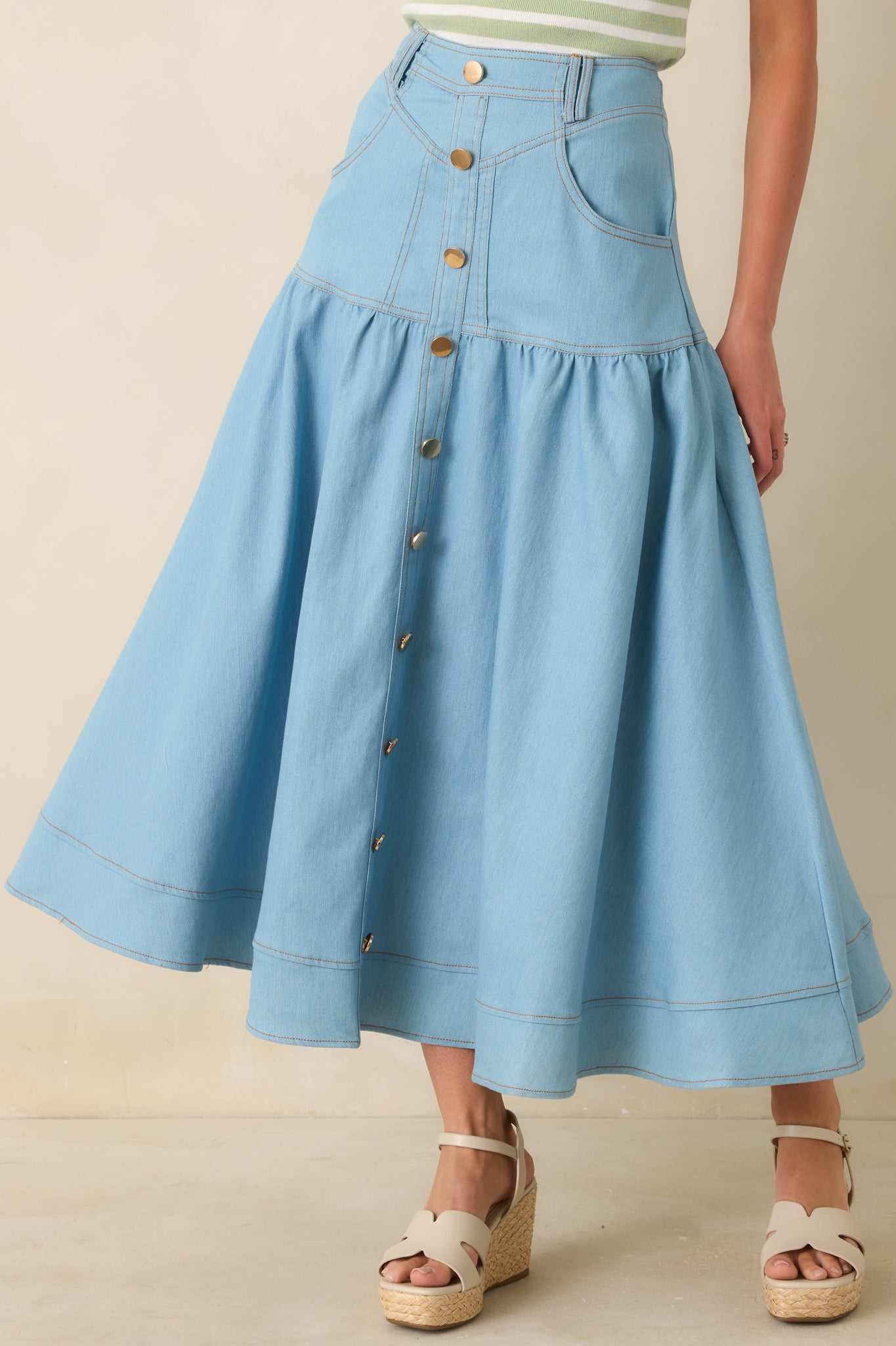 High-rise waistband on light wash denim maxi skirt with belt loops and tailoring.
