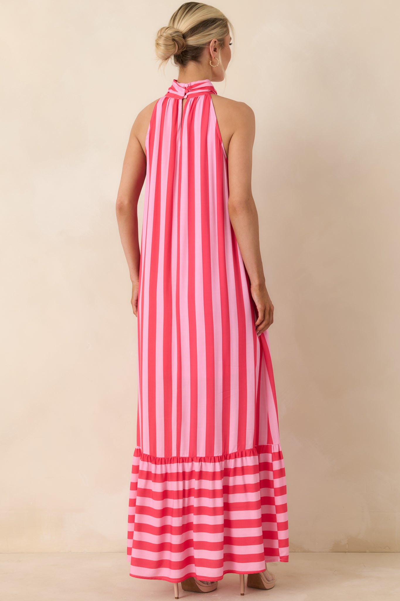 Rear view of halter dress with vertical fuchsia and pink stripes, relaxed fit, and tiered hem detail.