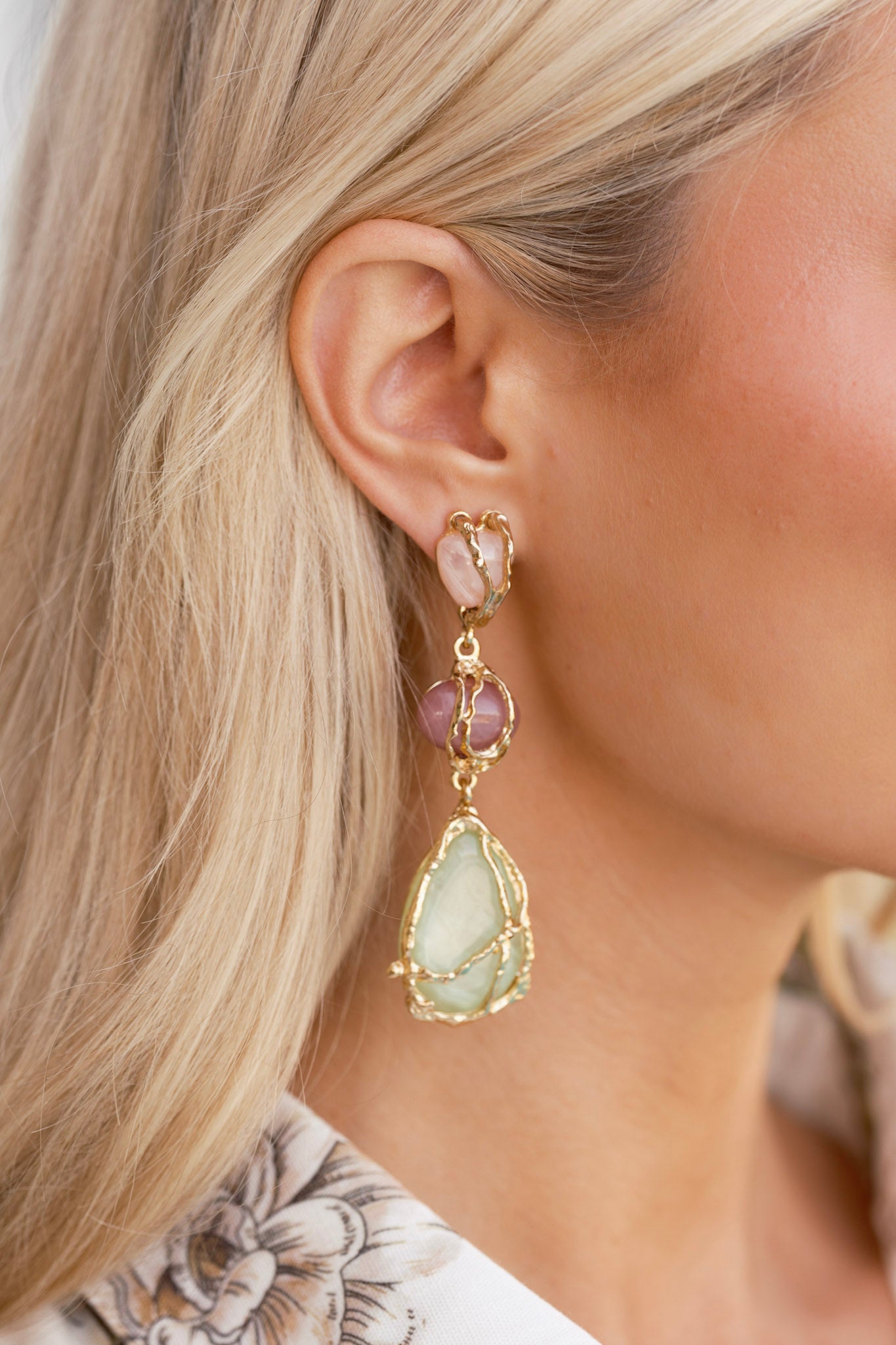 Close-up of one earring showing the secure post backing, textured gold wrap, and the glossy finish of each stone.