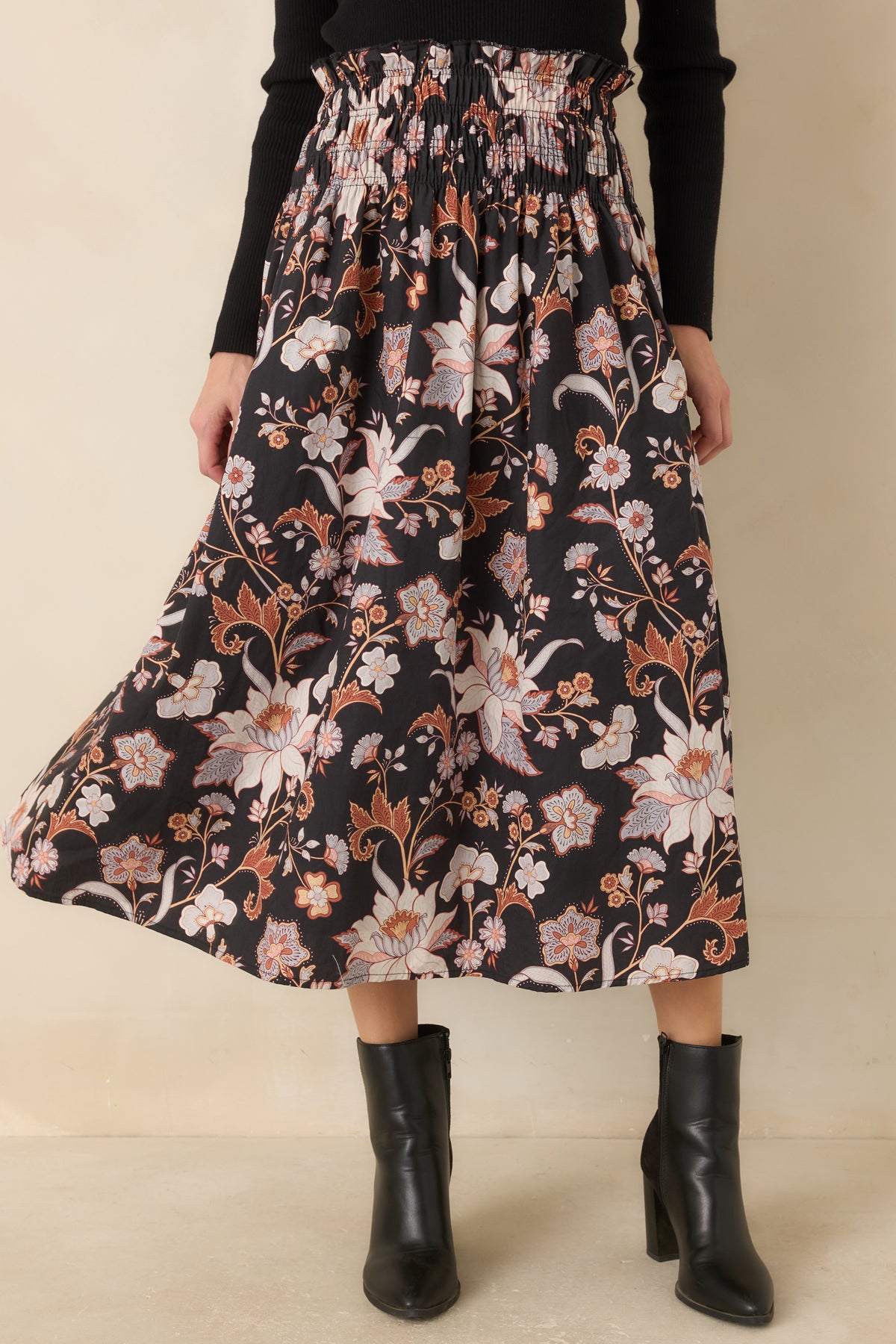 Functional side pockets blend into the full A-line shape of the black botanical-print midi skirt.