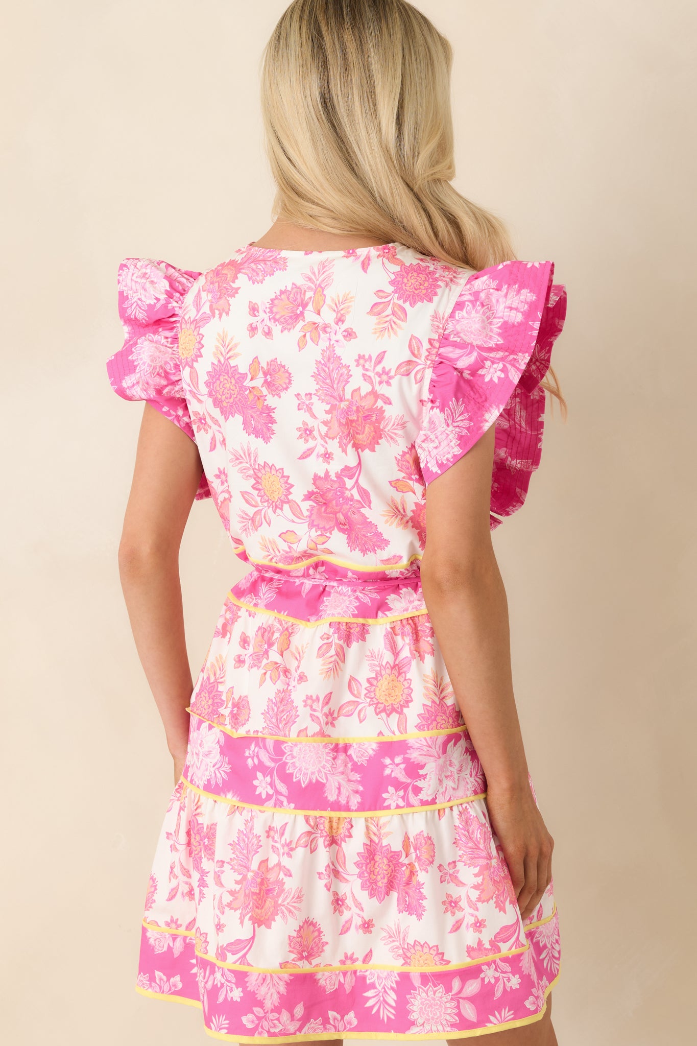 Rear view of pink floral mini dress with flutter sleeves and relaxed fit.