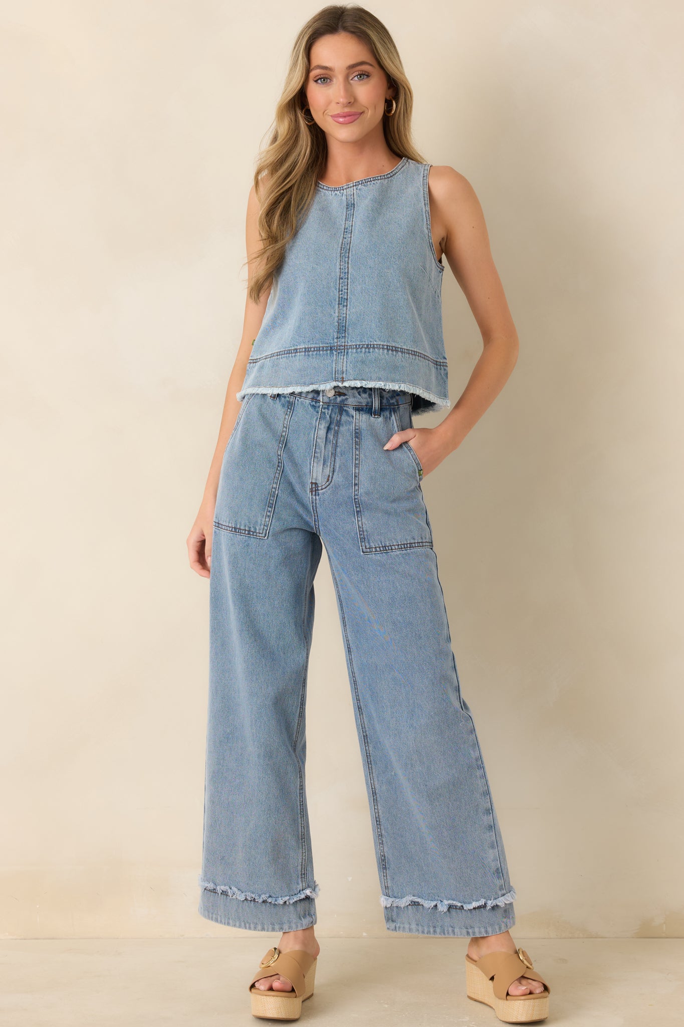 Light wash denim sleeveless top, with a structured fit, round neckline, and a softly frayed cropped hem.