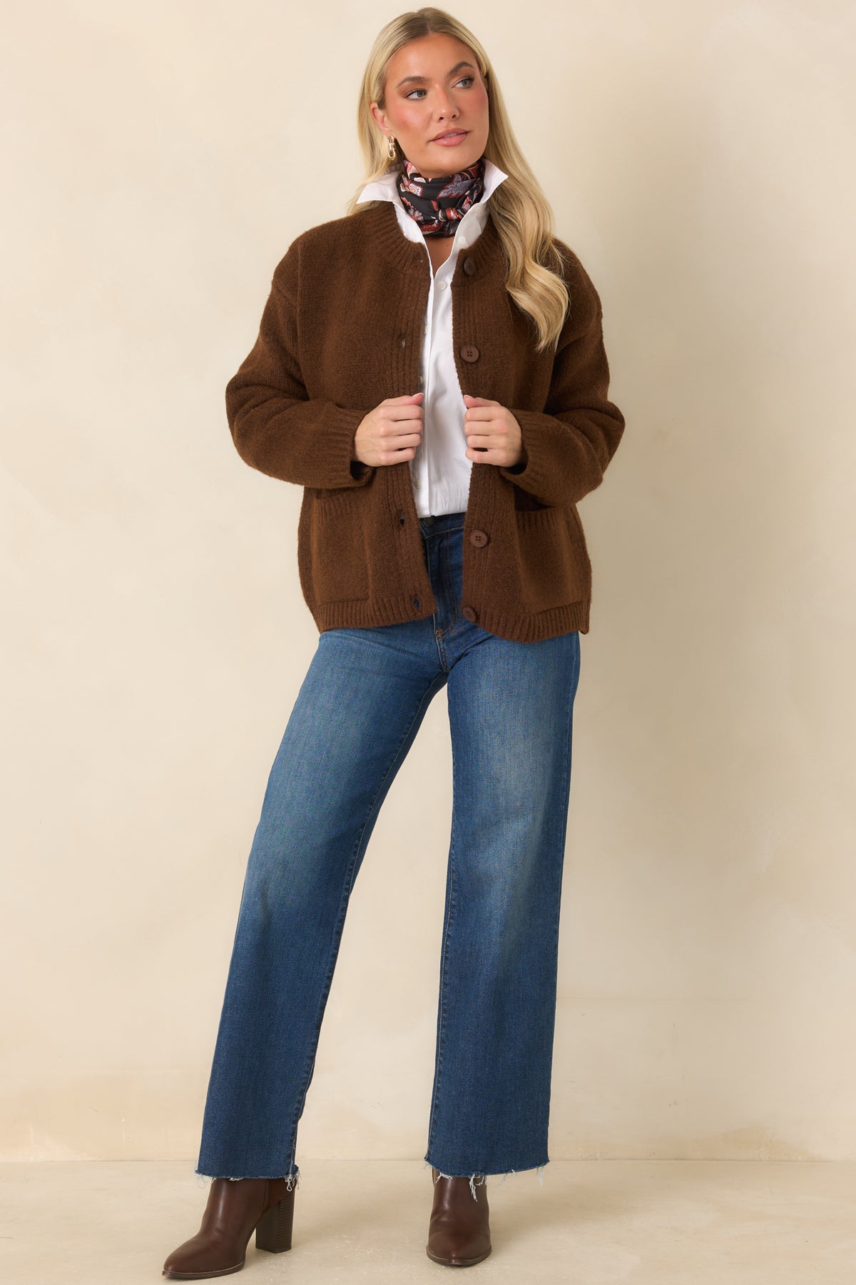 Chestnut brown knit cardigan with a ribbed crew neckline, tonal button front, and two front patch pockets.