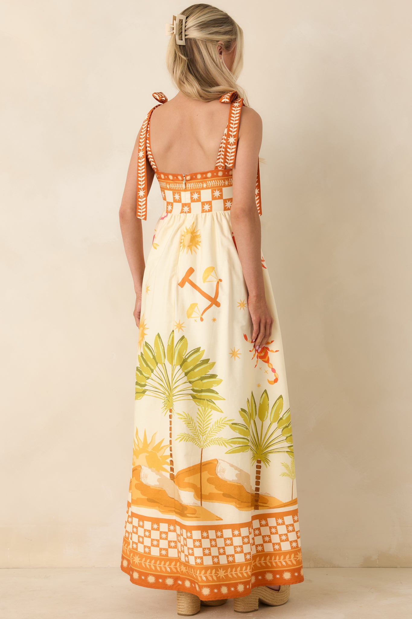Rear view of ivory maxi dress with concealed zipper, adjustable tie straps, and flowing skirt.