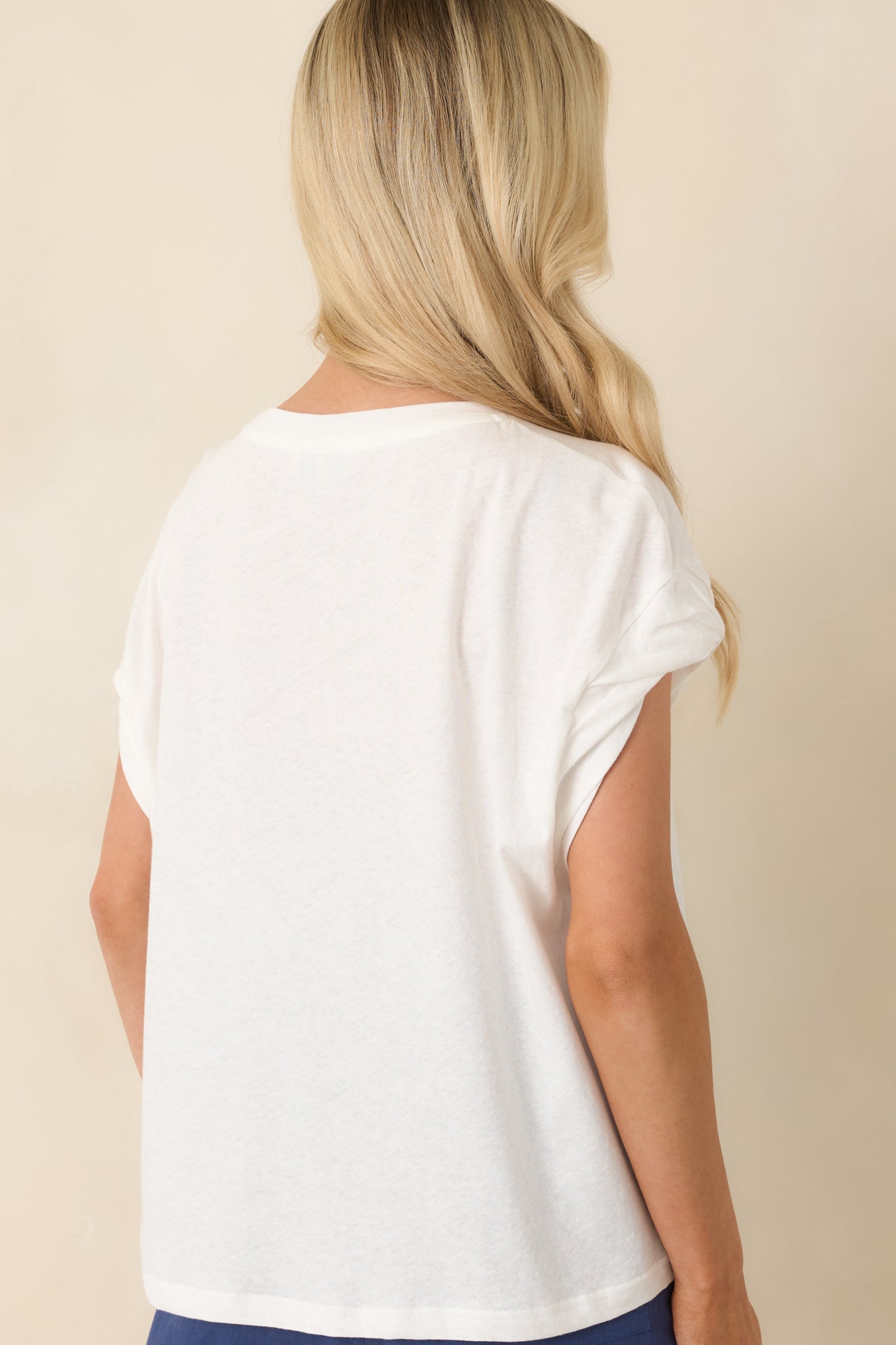 Rear view of white sleeveless t-shirt with relaxed fit and clean lines.