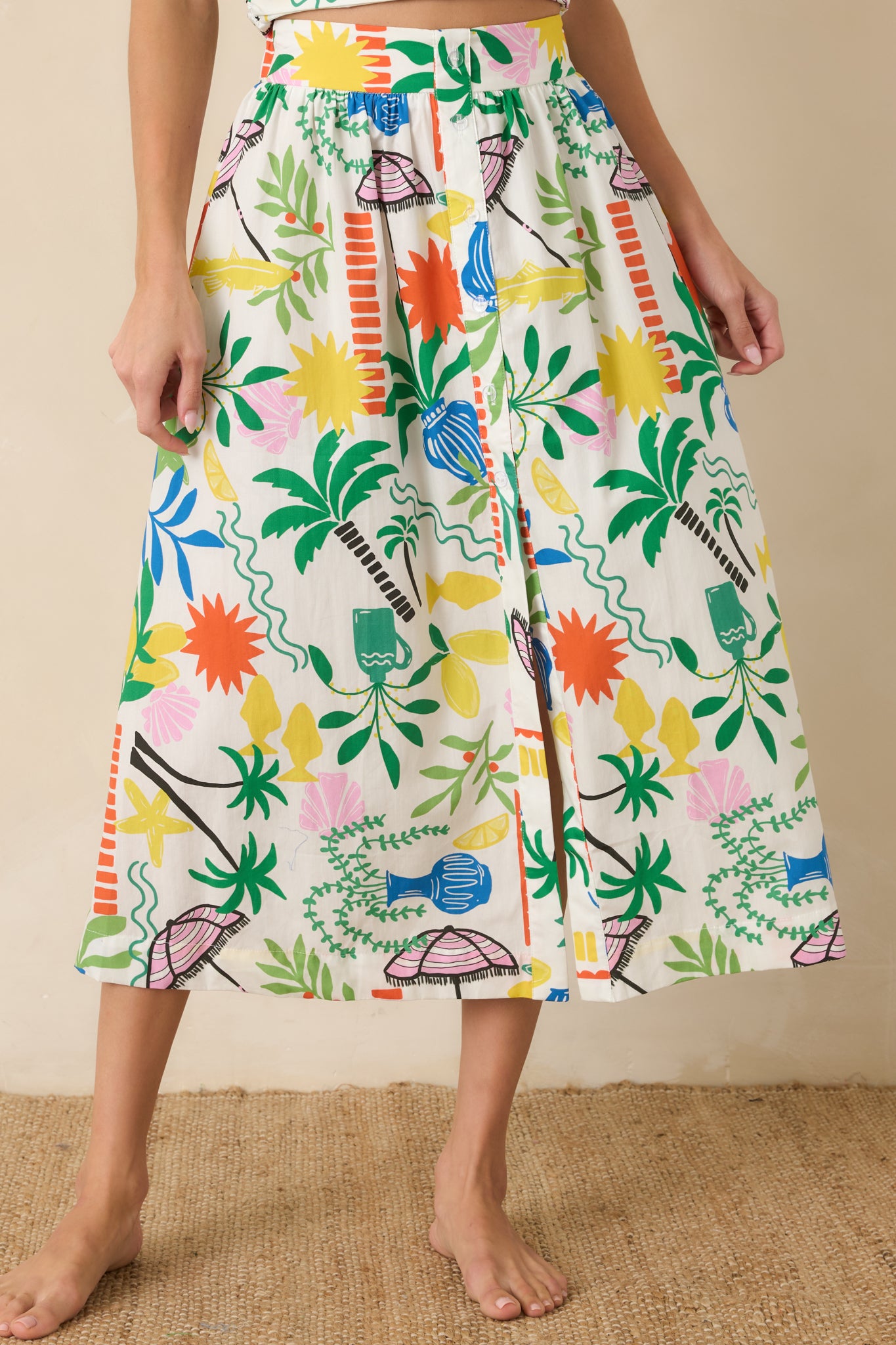 Detailed view of the high-rise waistband and functional front button accents on the printed midi skirt.