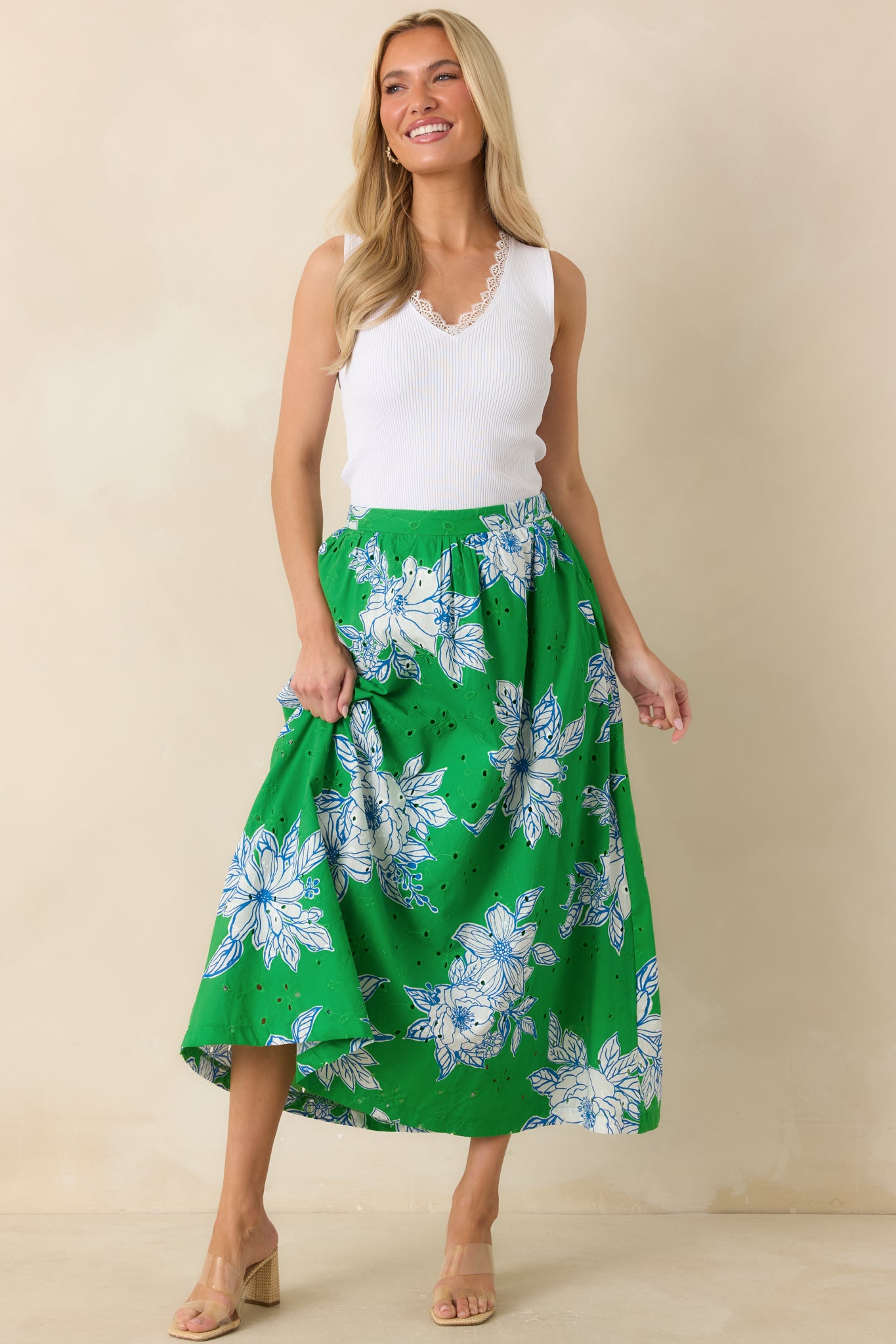 Midi-length skirt with a green floral print, elastic waistband, and airy eyelet texture designed for comfortable everyday wear.