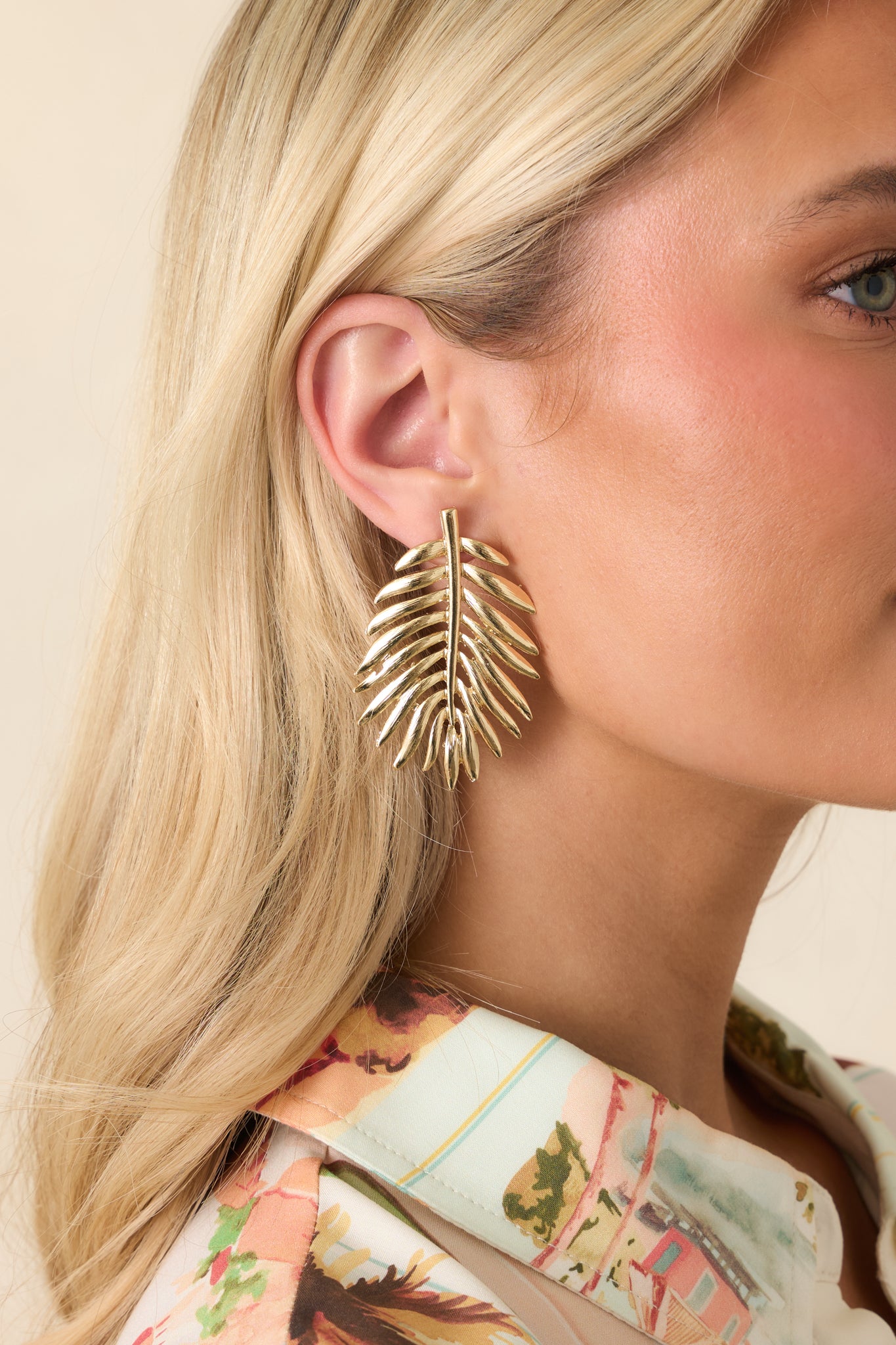Gold drop earrings with a palm leaf-inspired design, featuring an elongated silhouette that tapers to a soft point.