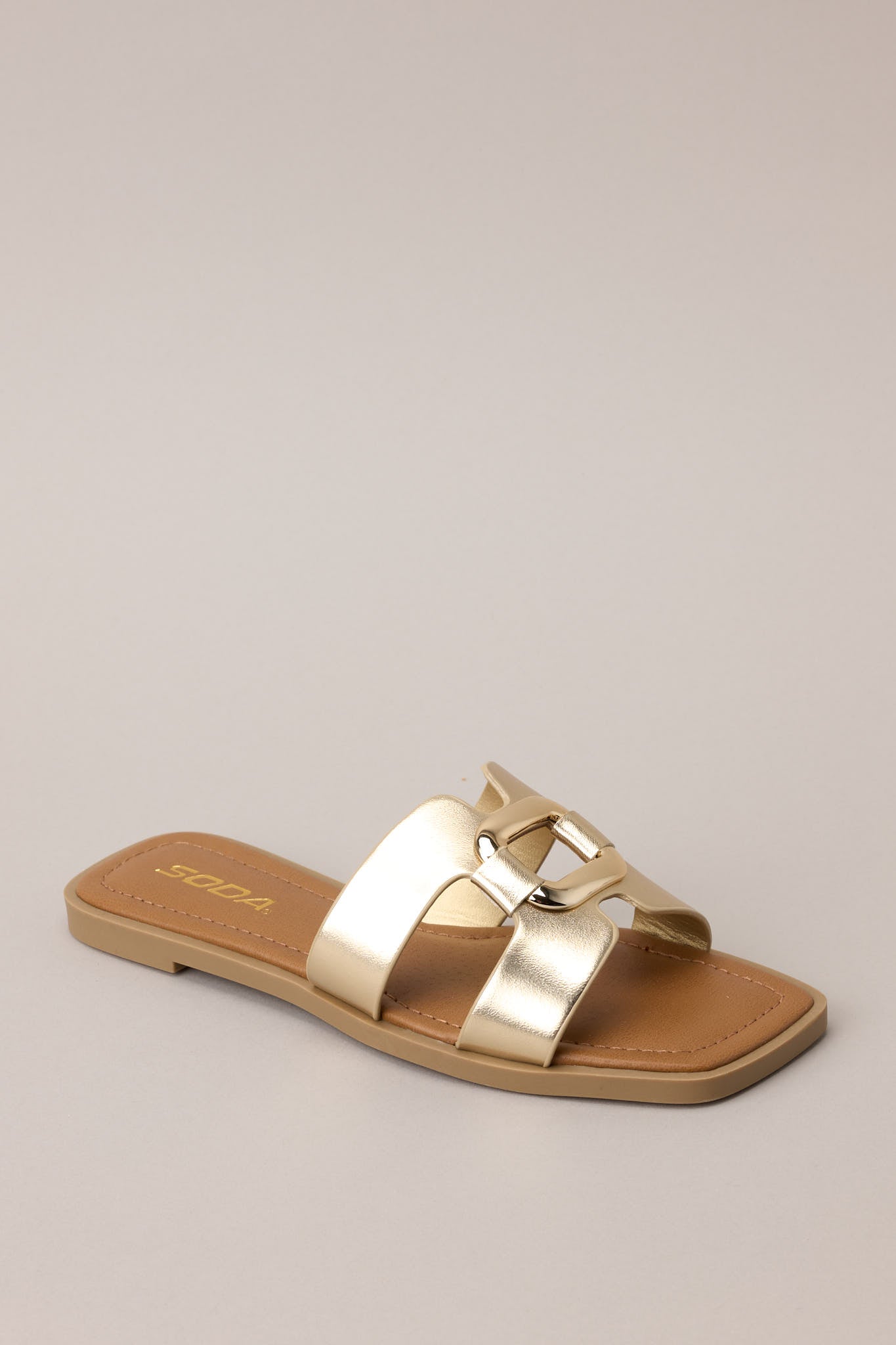 Three-quarter view of the metallic gold sandals highlighting the open silhouette and modern shape.
