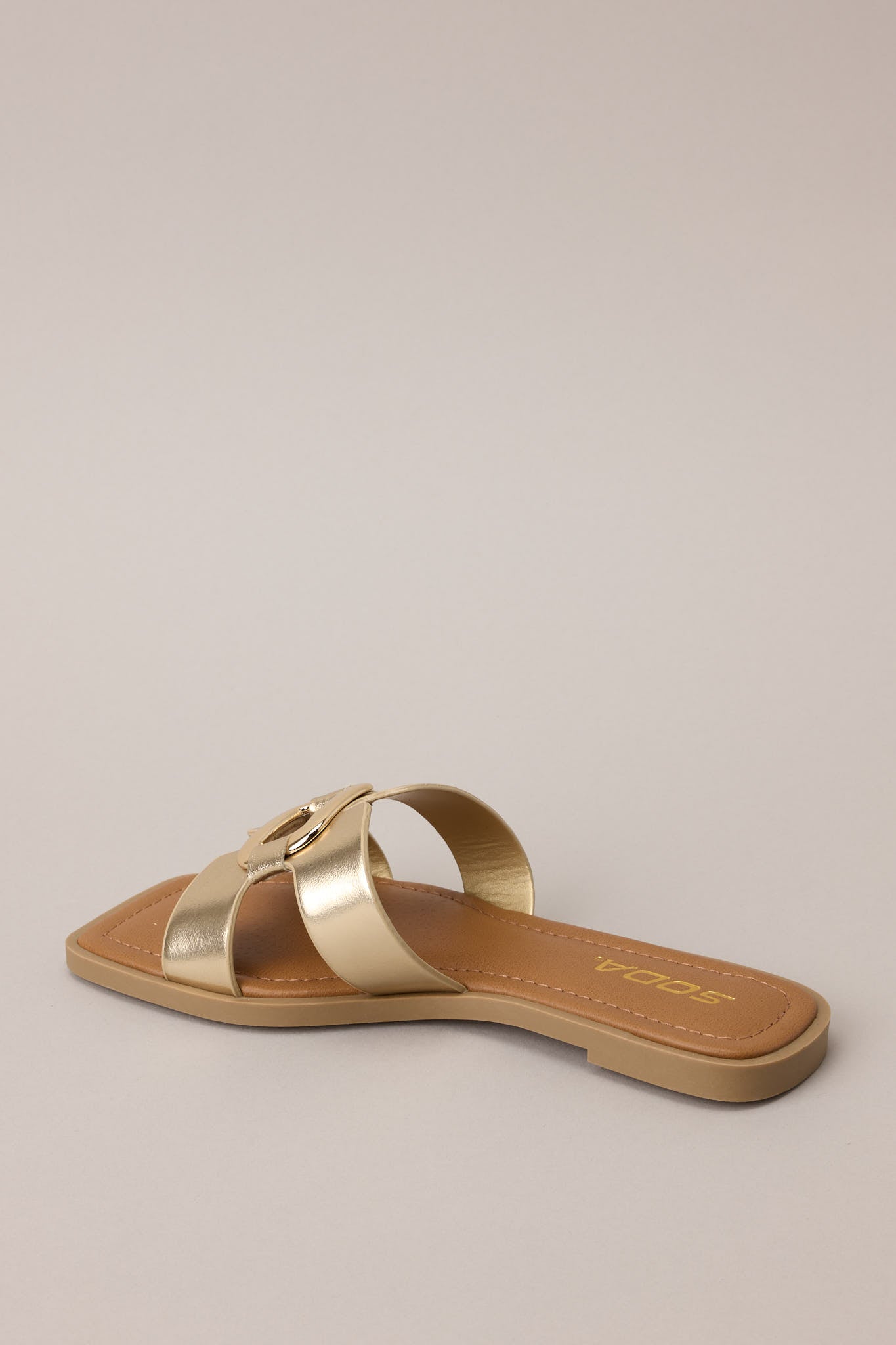 Back view of the gold slip-on sandals displaying the open back and flat sole construction.