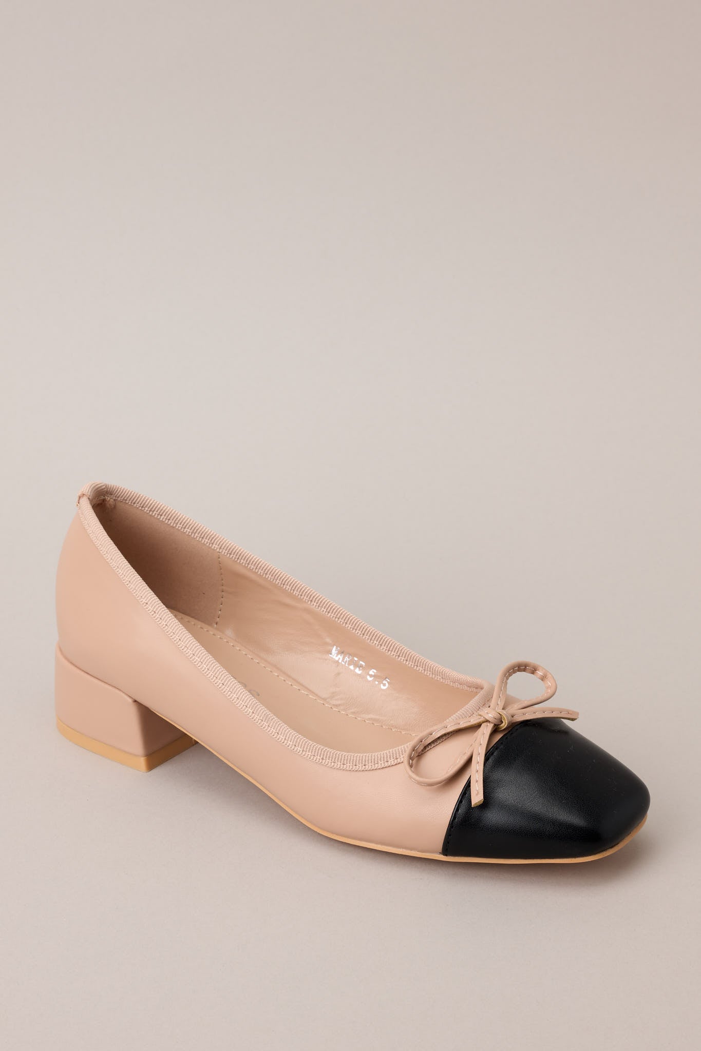 Top-down view of one beige heel highlighting symmetry and bow accents.