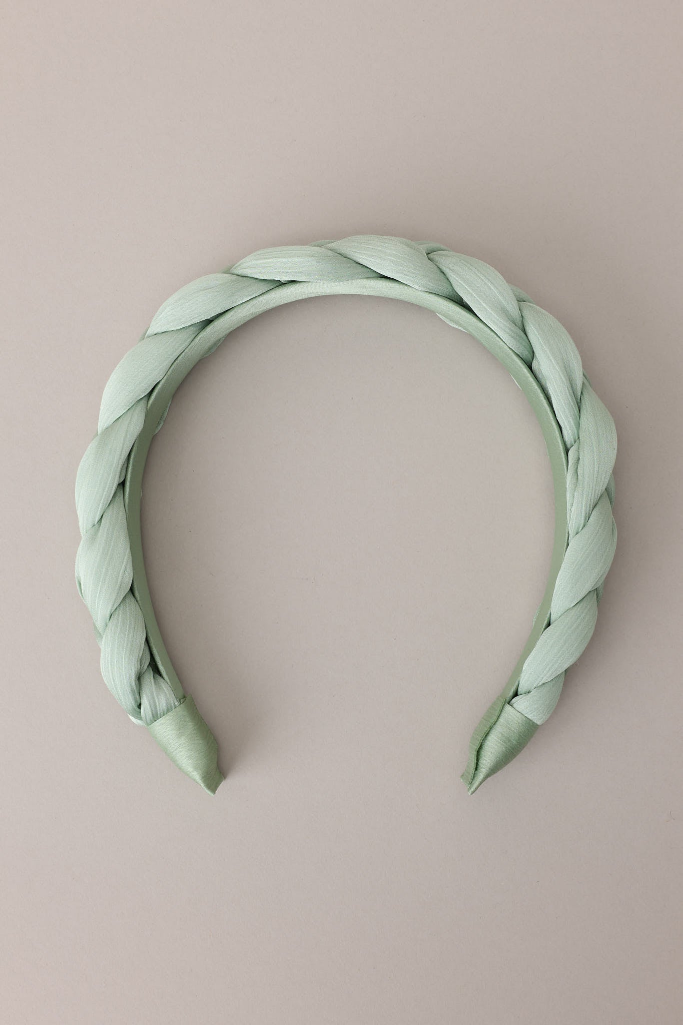 Flat front view of this headband that features a thick, soft material, and a braided texture. 