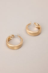 Close up view of these earrings that feature gold hardware, a matte finish, and a functional clasp closure.