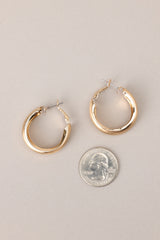 Size comparison of these earrings that feature gold hardware, a matte finish, and a functional clasp closure.