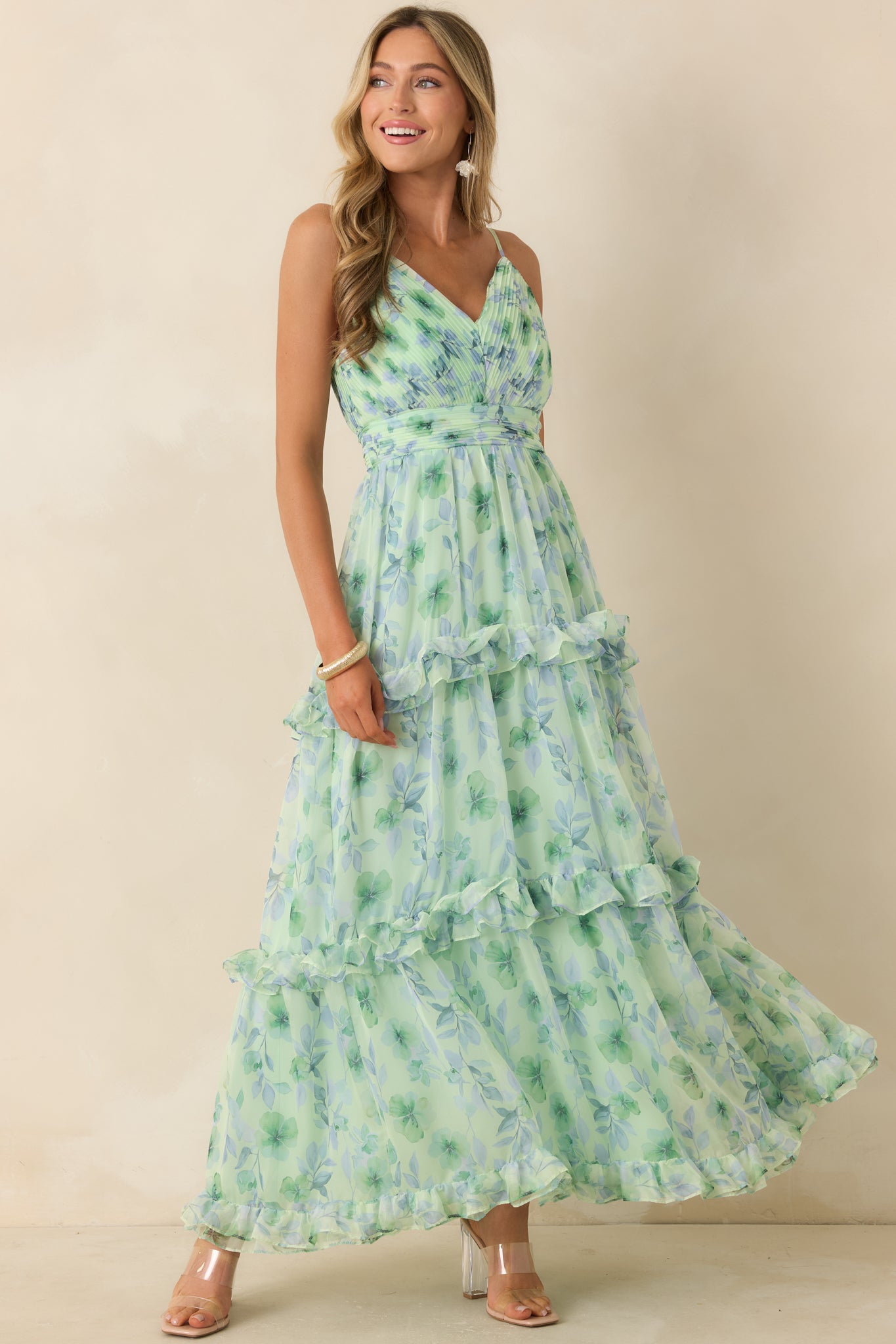 Green floral maxi dress with a softly draped silhouette and layered ruffle accents throughout the skirt.